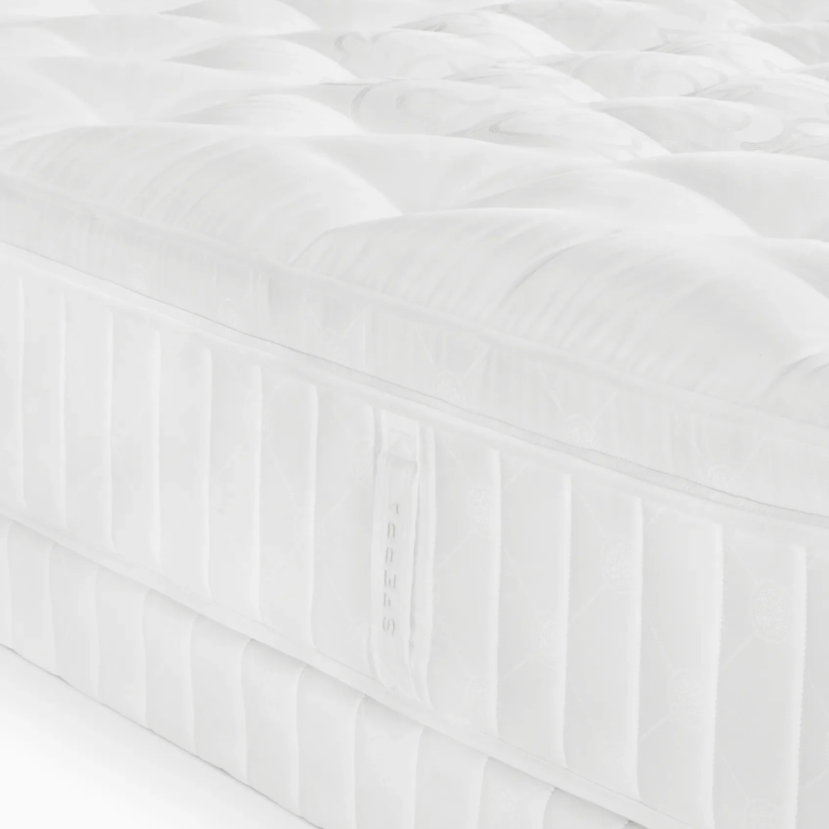 Close-up of a white, quilted luxury Sferra Nuvole CV Pillowtop Mattress with visible stitching and a fabric handle on the side.