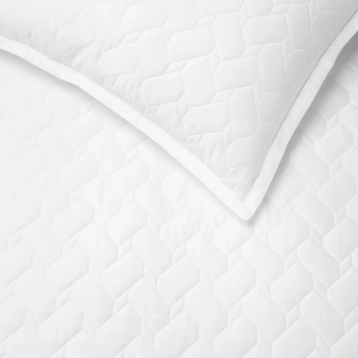 Close-up of White Sferra Palatino Quilt and Shams, both featuring a crisp geometric, textured pattern