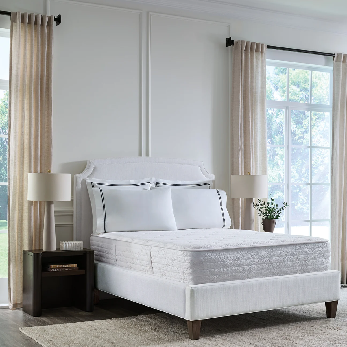 A Sferra Sognofacile Mattress in a Box, flanked by lamps, beige curtains, and large windows.