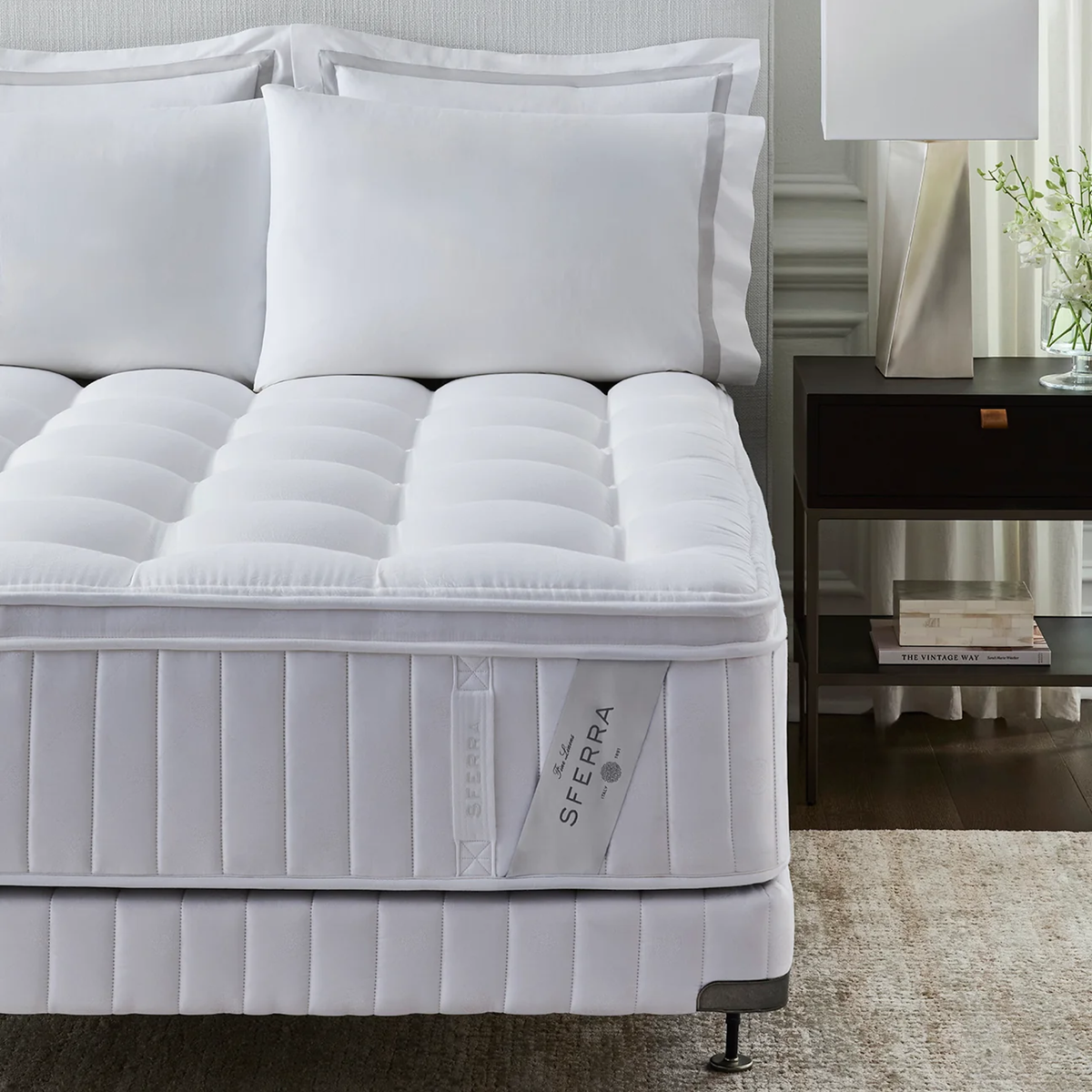 A Sferra Sonno Notte CV Pillowtop Mattress beside a dark nightstand with a lamp.