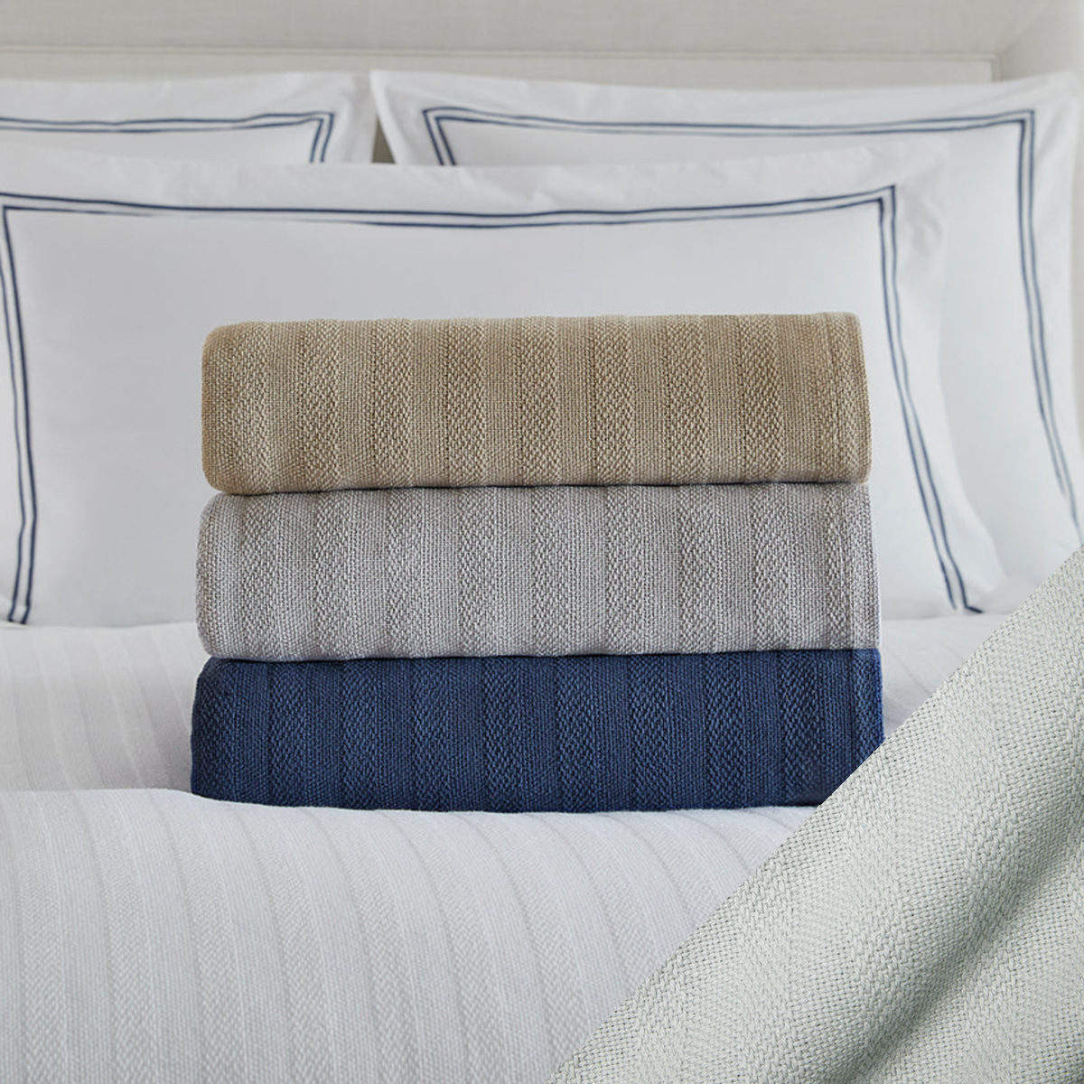 Stack of Folded Sferra Tavira Blanket on a Bed with Flint Swatch