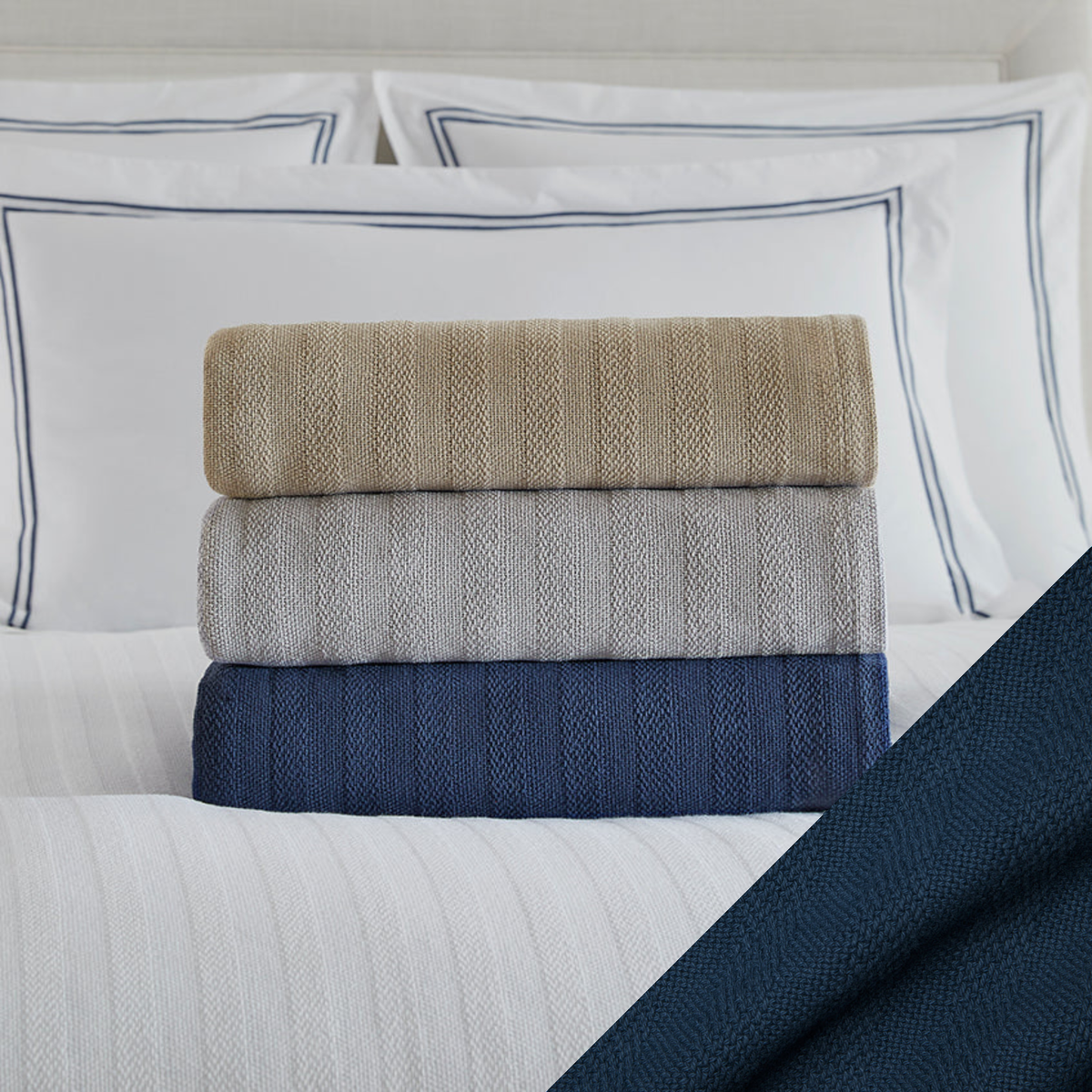 Stack of Folded Sferra Tavira Blanket on a Bed with Navy Swatch