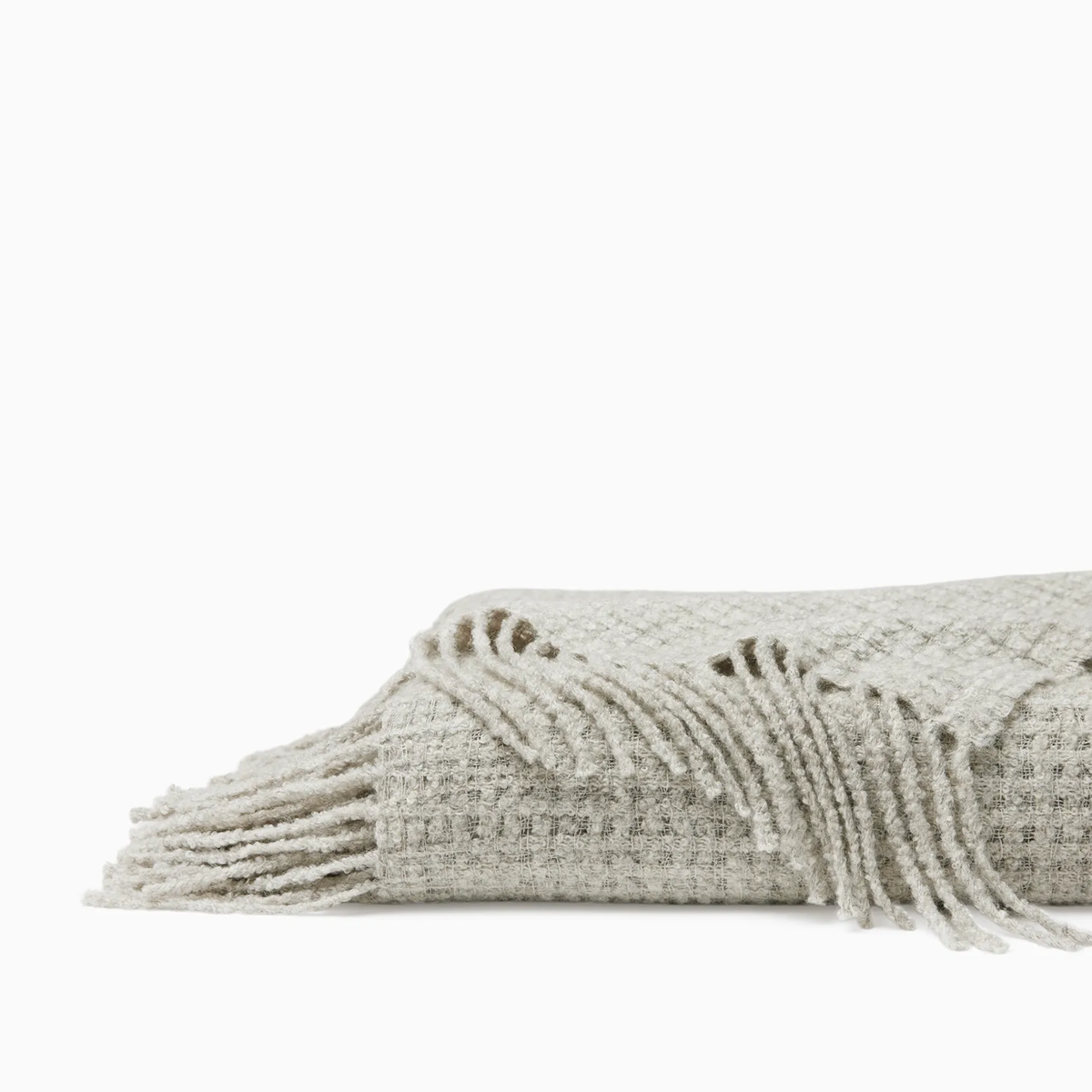 Folded Sferra Terranova Throw in Grey color showing its twisted fringes
