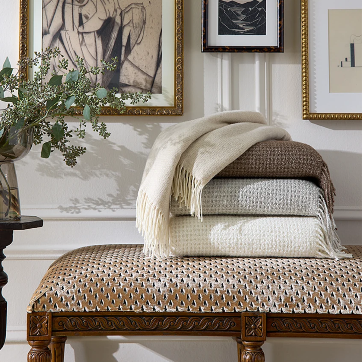 A stack of Sferra Terranova throws rests on an ottoman