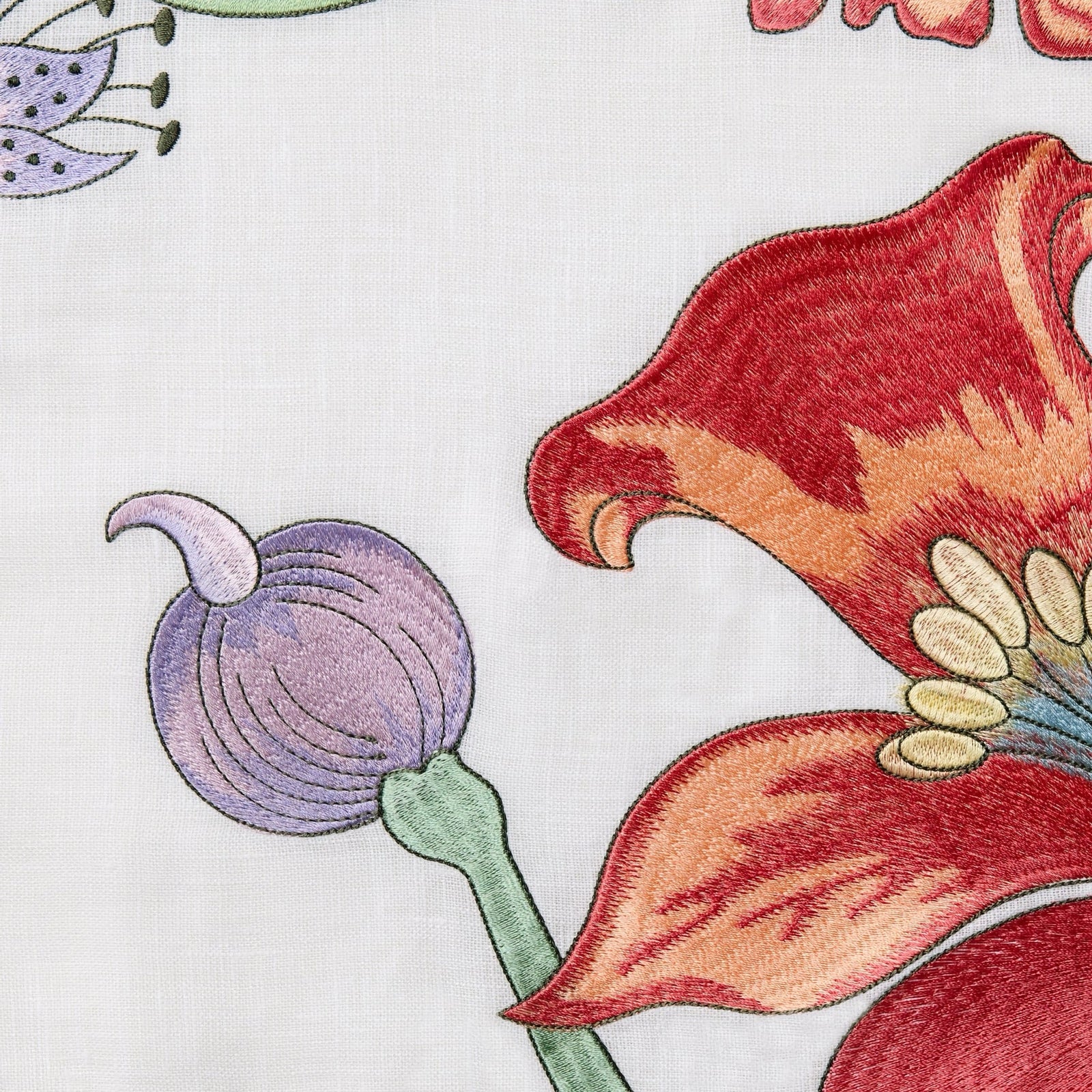 A light blue armchair with a botanical decorative pillow and gray throw blanket next to a table with yellow flowers.