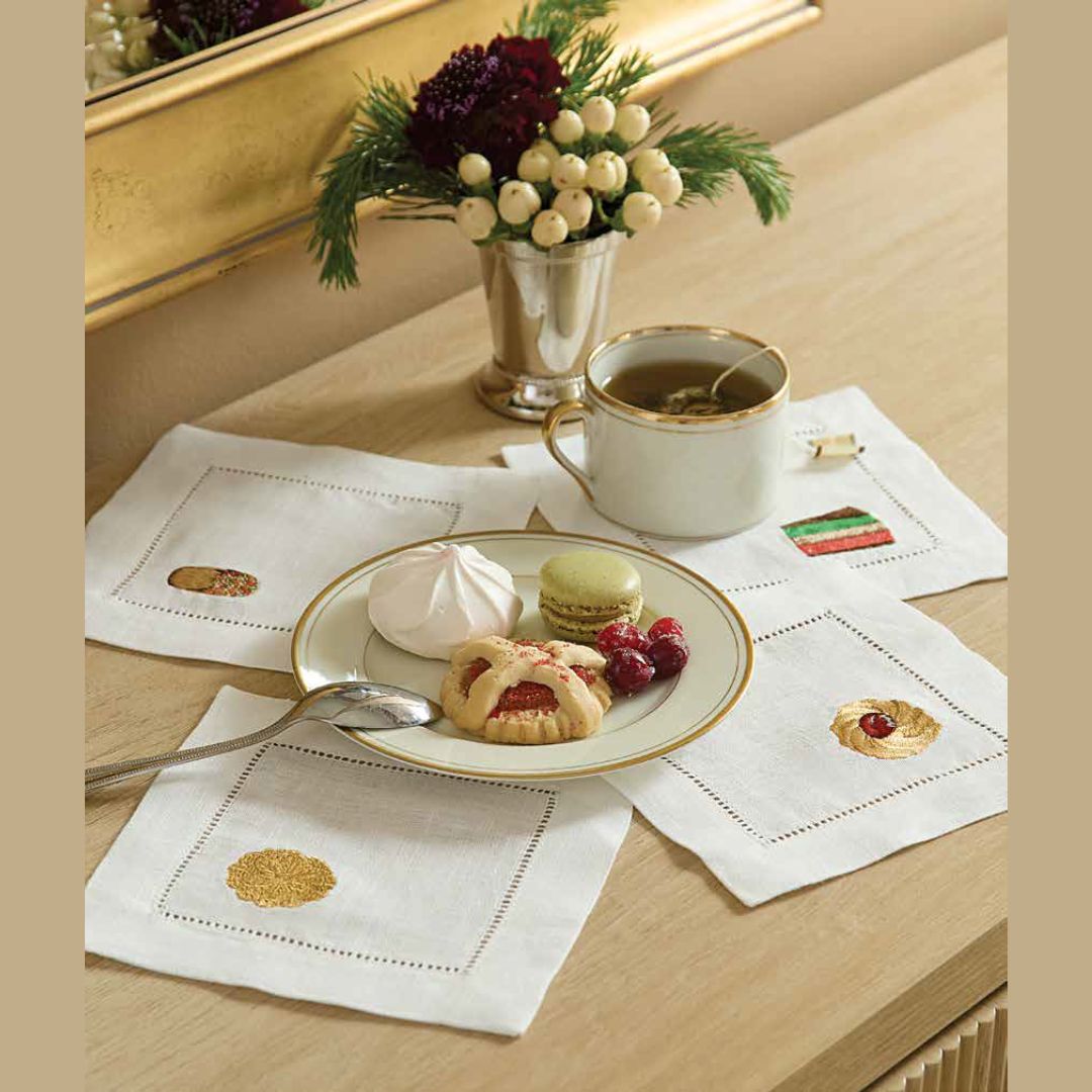 Sferra Biscotto cocktail napkins arranged around a plate of cookies and a cup of tea