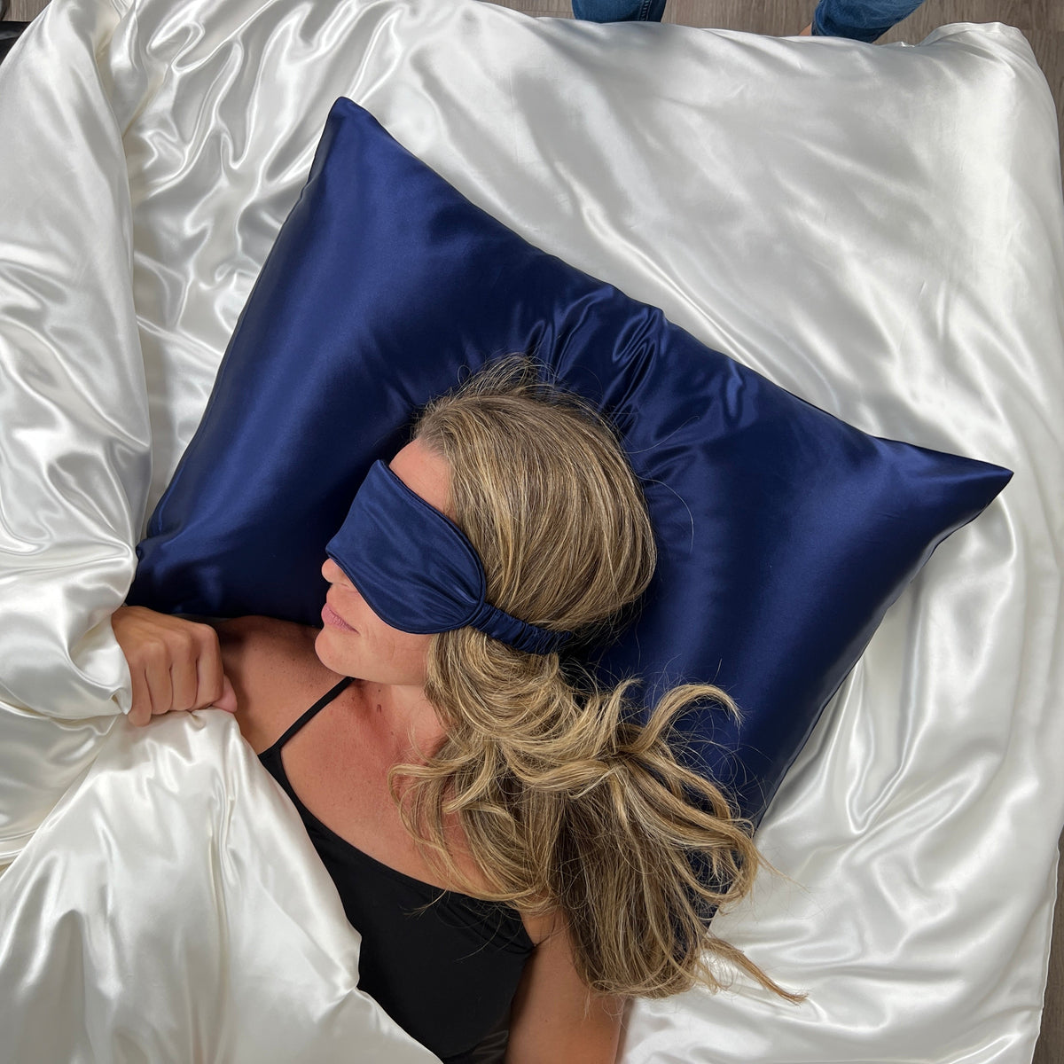 Woman sleeping on a Navy pillow with a matching silk sleep mask for eyes for ultimate comfort