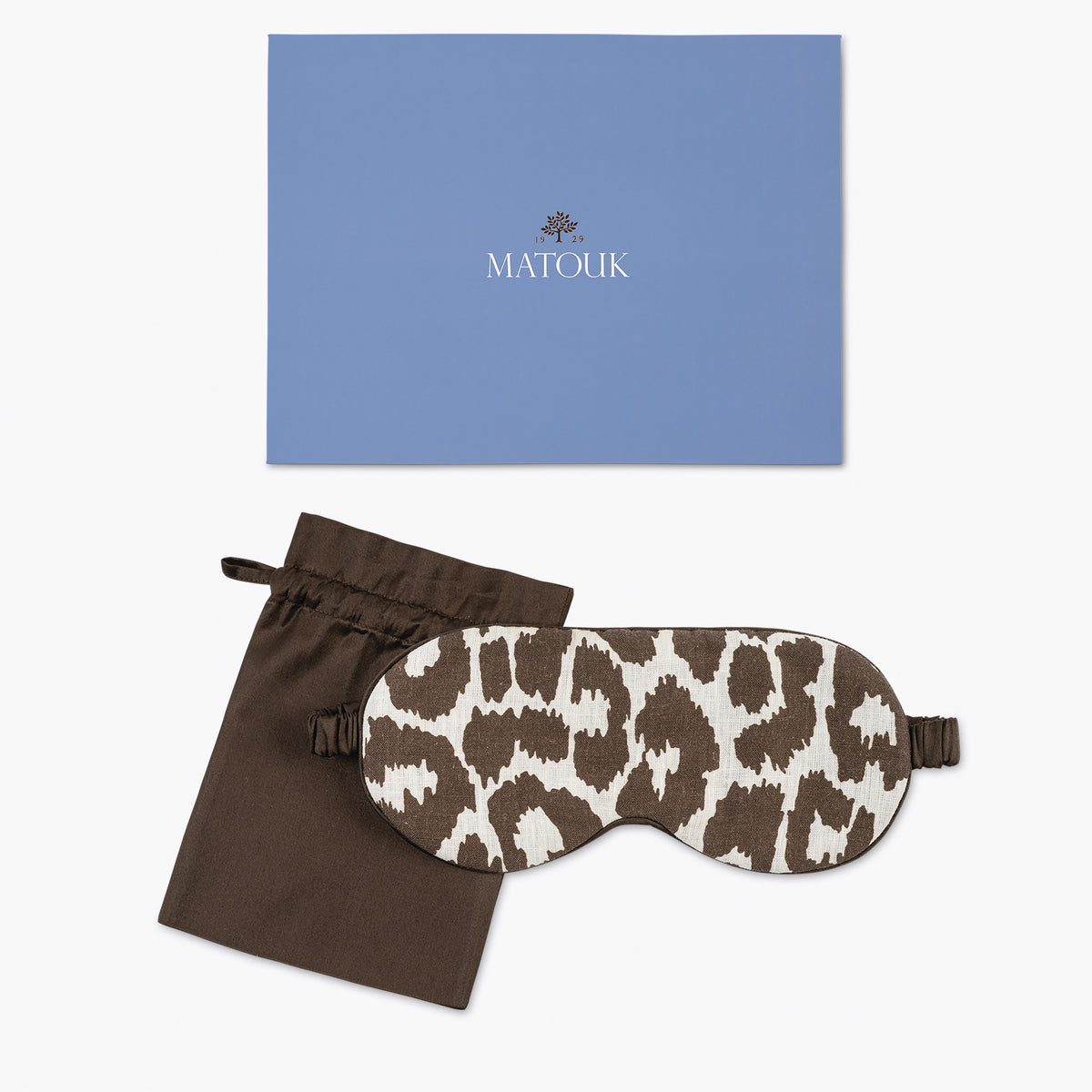 Leopard print eye mask with brown pouch and blue Matouk branded card on a white background