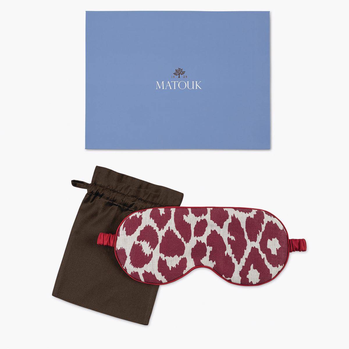 Sleep mask with purple leopard print design, black drawstring bag, and blue Matouk branded box on a white background.