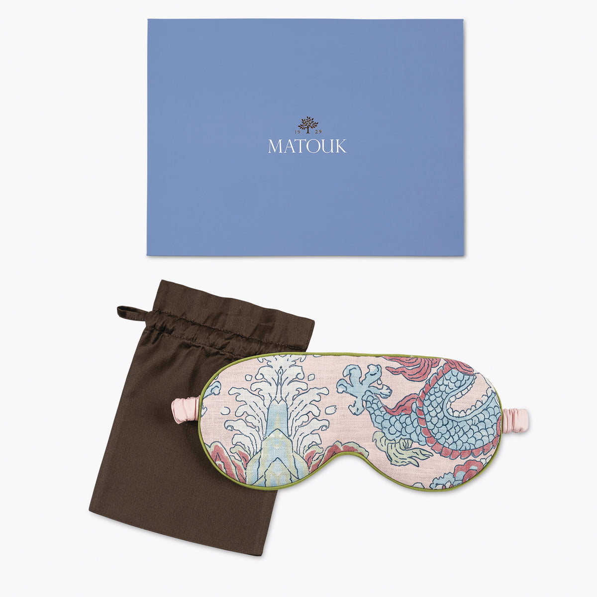 Sleep mask with floral design, brown drawstring bag, and blue Matouk box on a white background