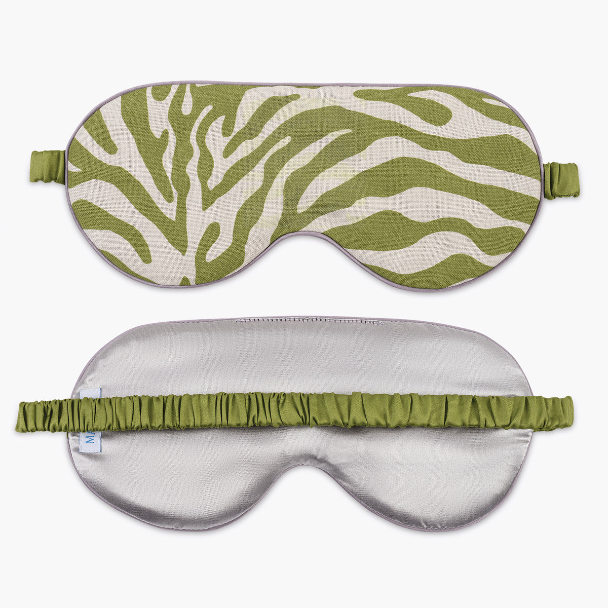 Matouk Schumacher sleep masks: one green-white zebra, one silver, both with green elastic bands.