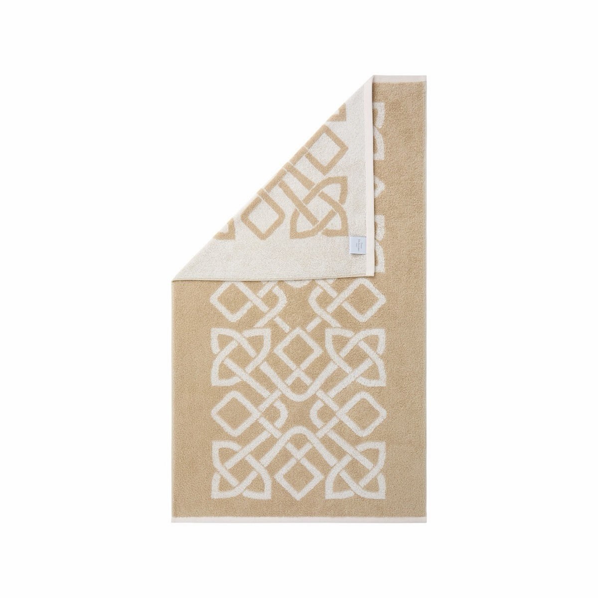 Rectangular Yves Delorme Apollon Bath Towel in Dune color and white knot pattern, corner folded to show reverse design