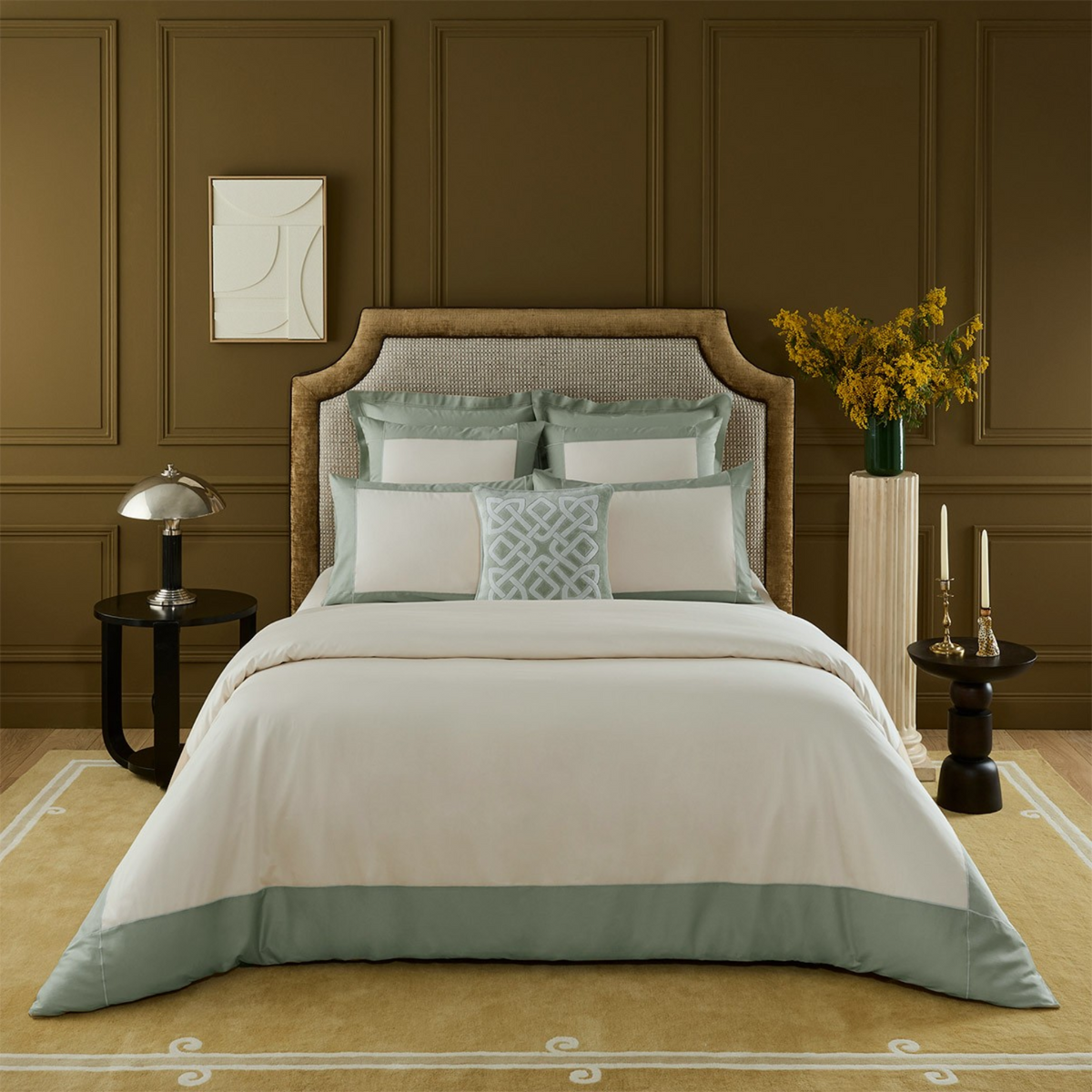 A neatly made bed with Yves Delorme Apollon Bedding Collection in Veronese Color