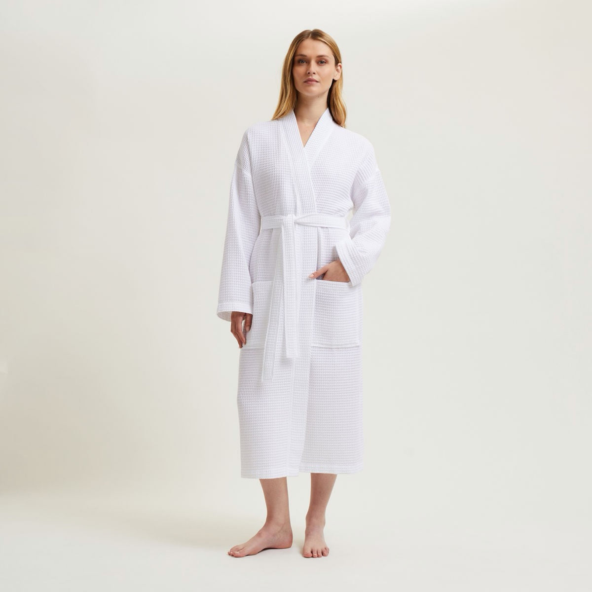 Woman standing barefoot in a Blanc Yves Delorme Astreena Bath Robe, with one hand in a pocket.