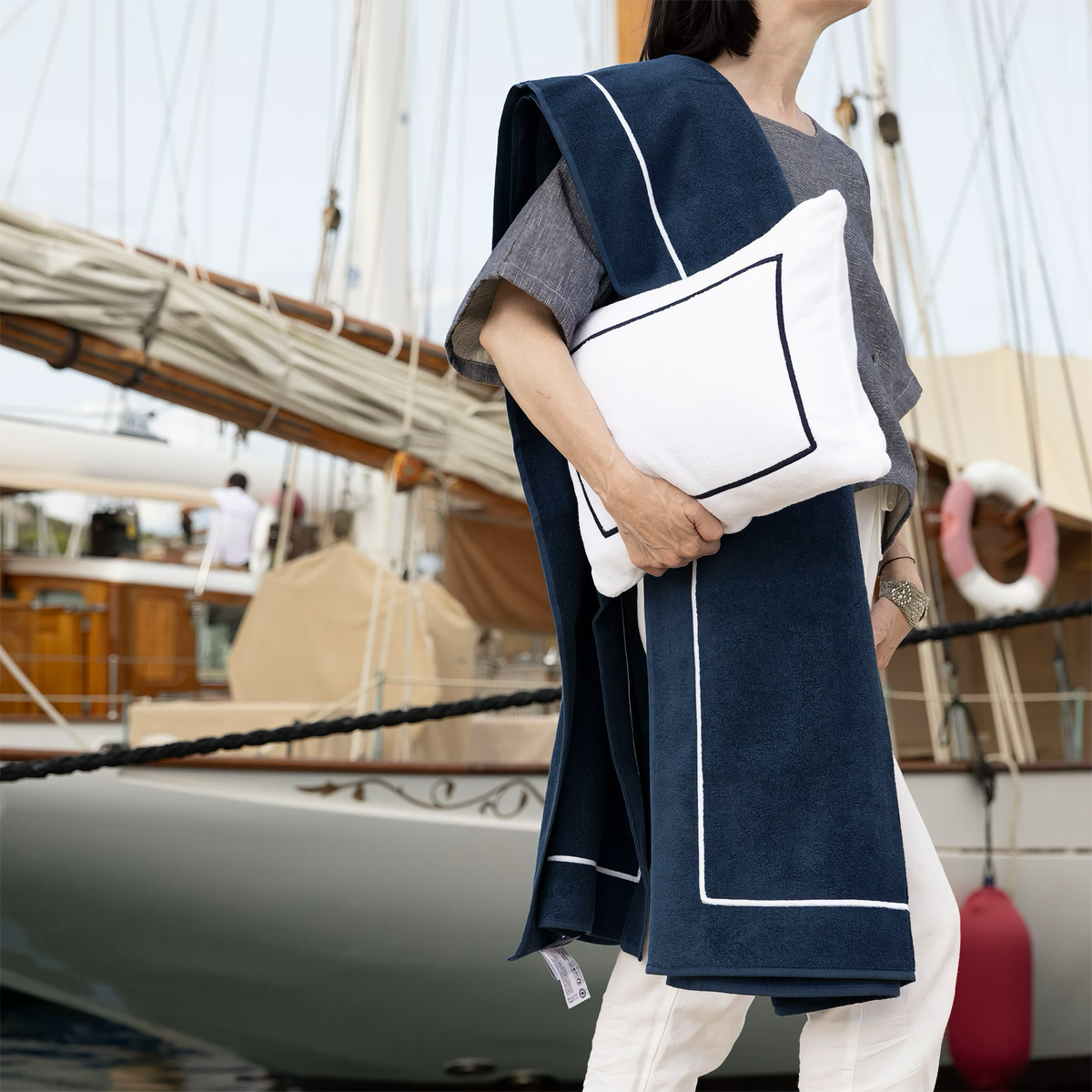 Woman carrying a Yves Delorme Croisiere Beach Pillow in Blanc