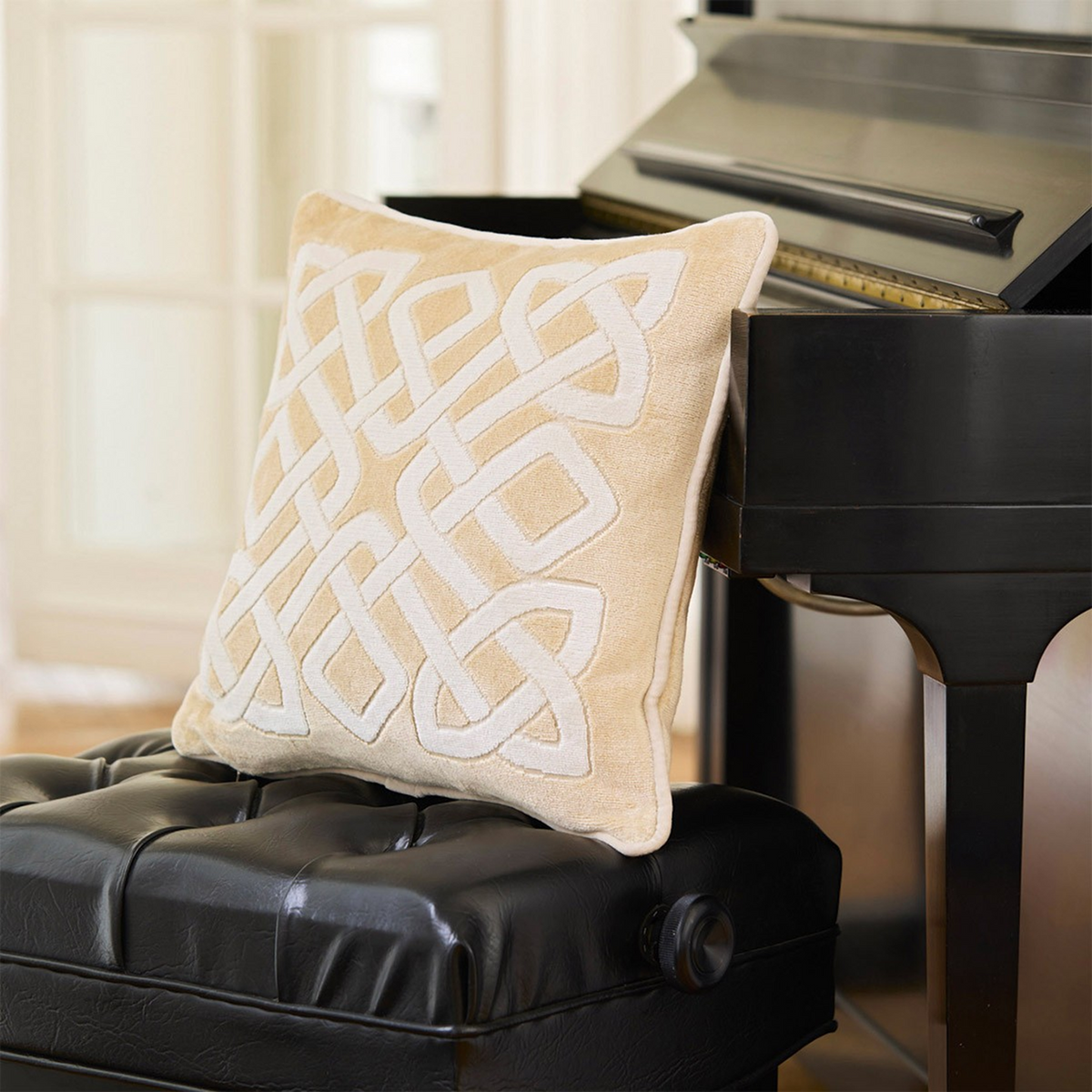 Decorative Pillow of Yves Delorme Entrelac Dune Bedding Collection on a dark leathered chair and piano