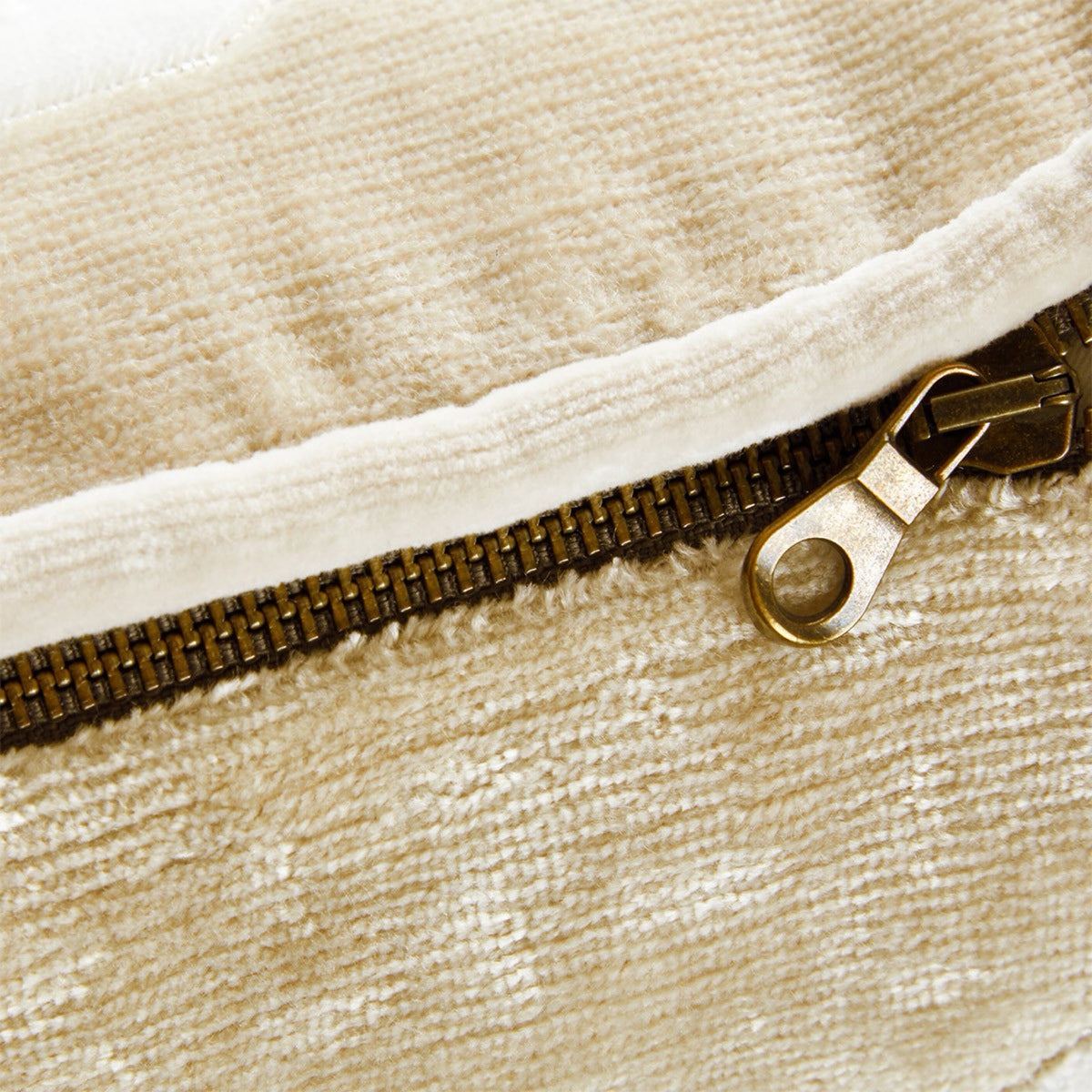 Close-up of a metal zipper on a textured beige Genoa velvet cushion cover.