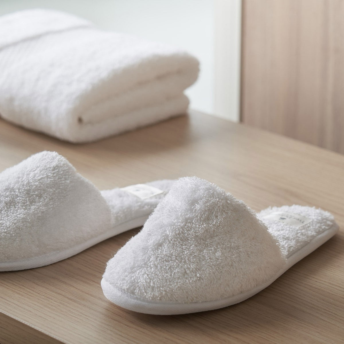 Pair of Blanc Yves Delorme Etoile Slippers on a wooden surface