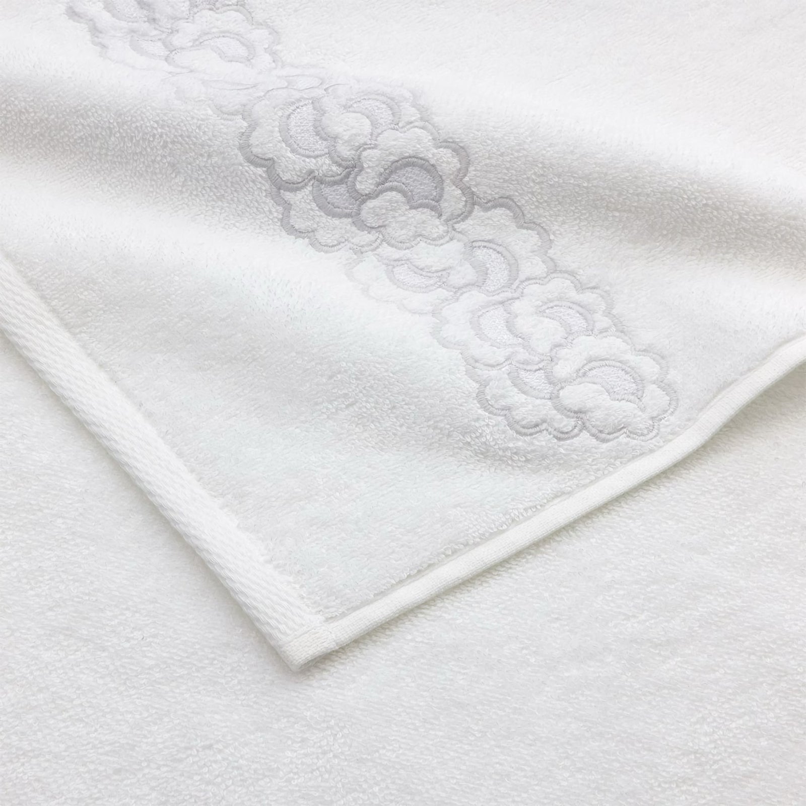 Stack of Yves Delorme Festons Bath Towels on a stool