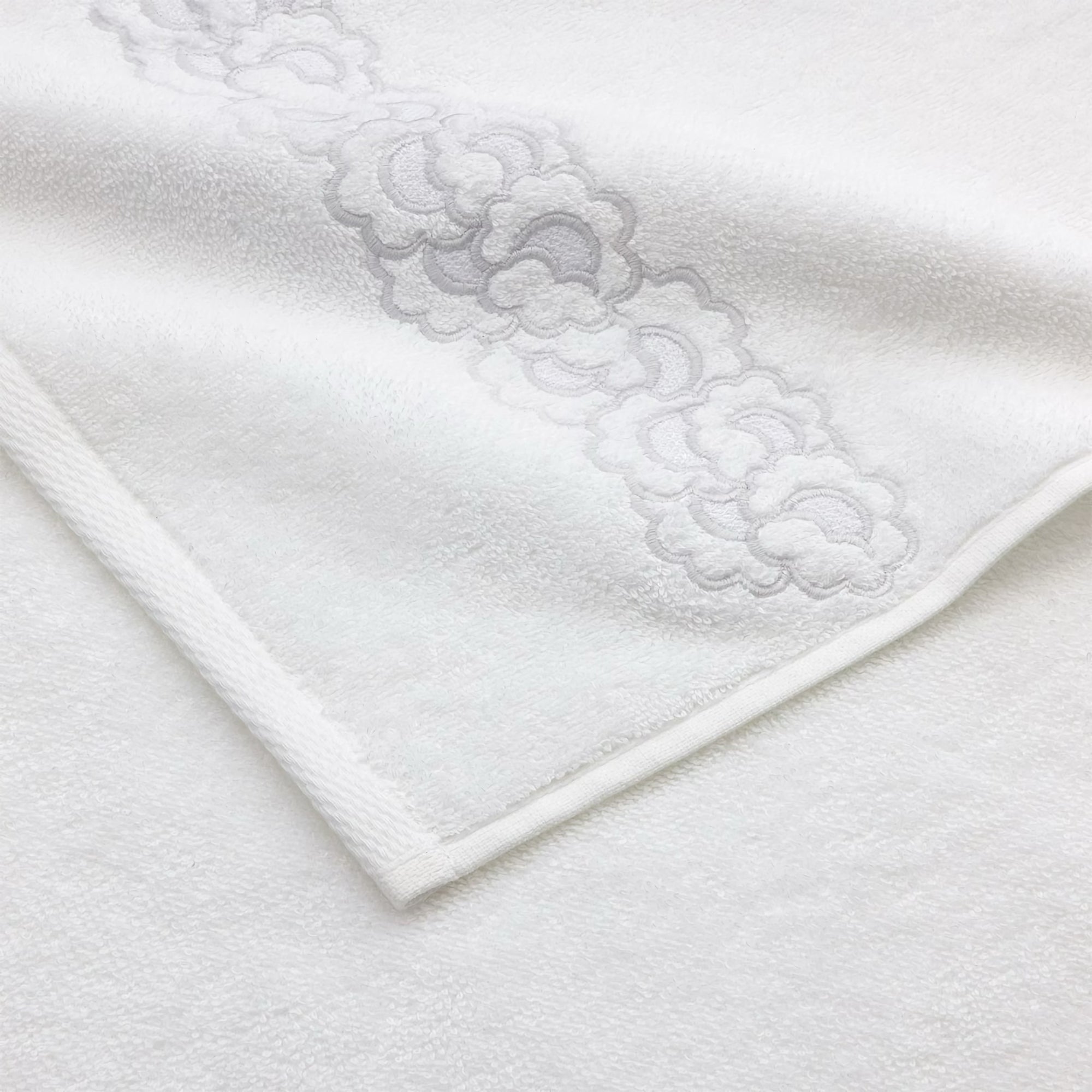 Stack of Yves Delorme Festons Bath Towels on a stool