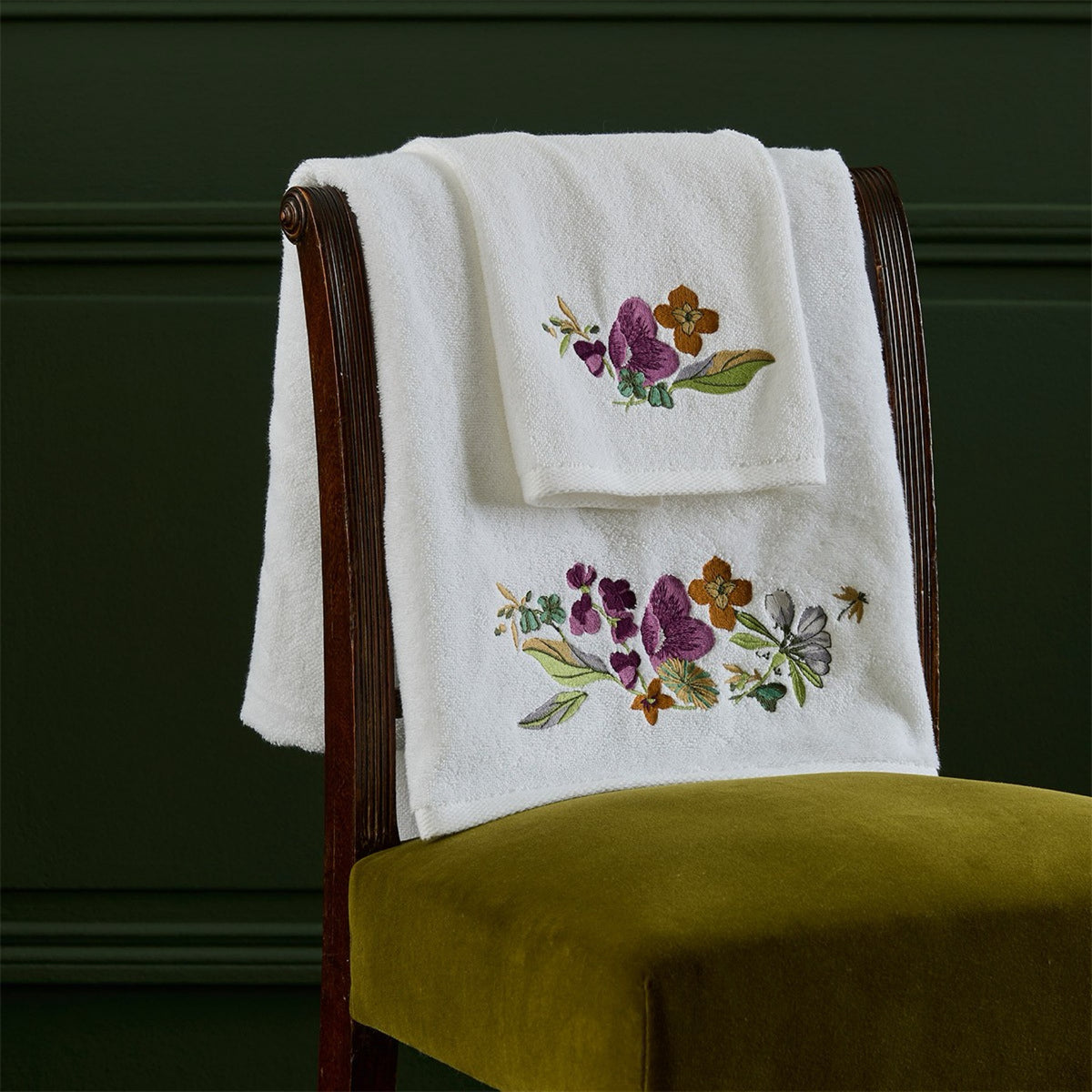 Yves Delorme Fleurs Bath Towels hanging on a chair