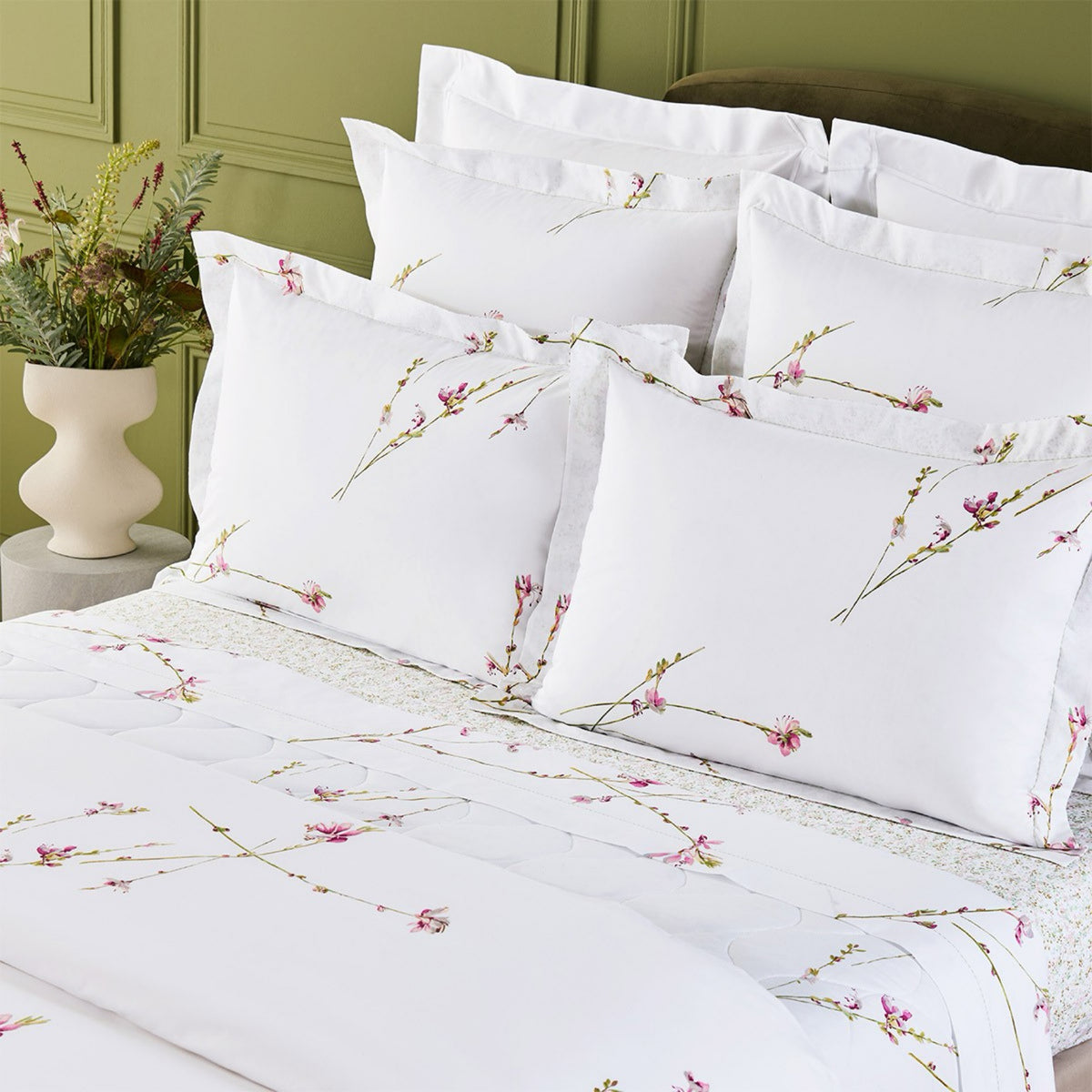 Closeup of Yves Delorme Gaura Bedding Collection, set against a green wall