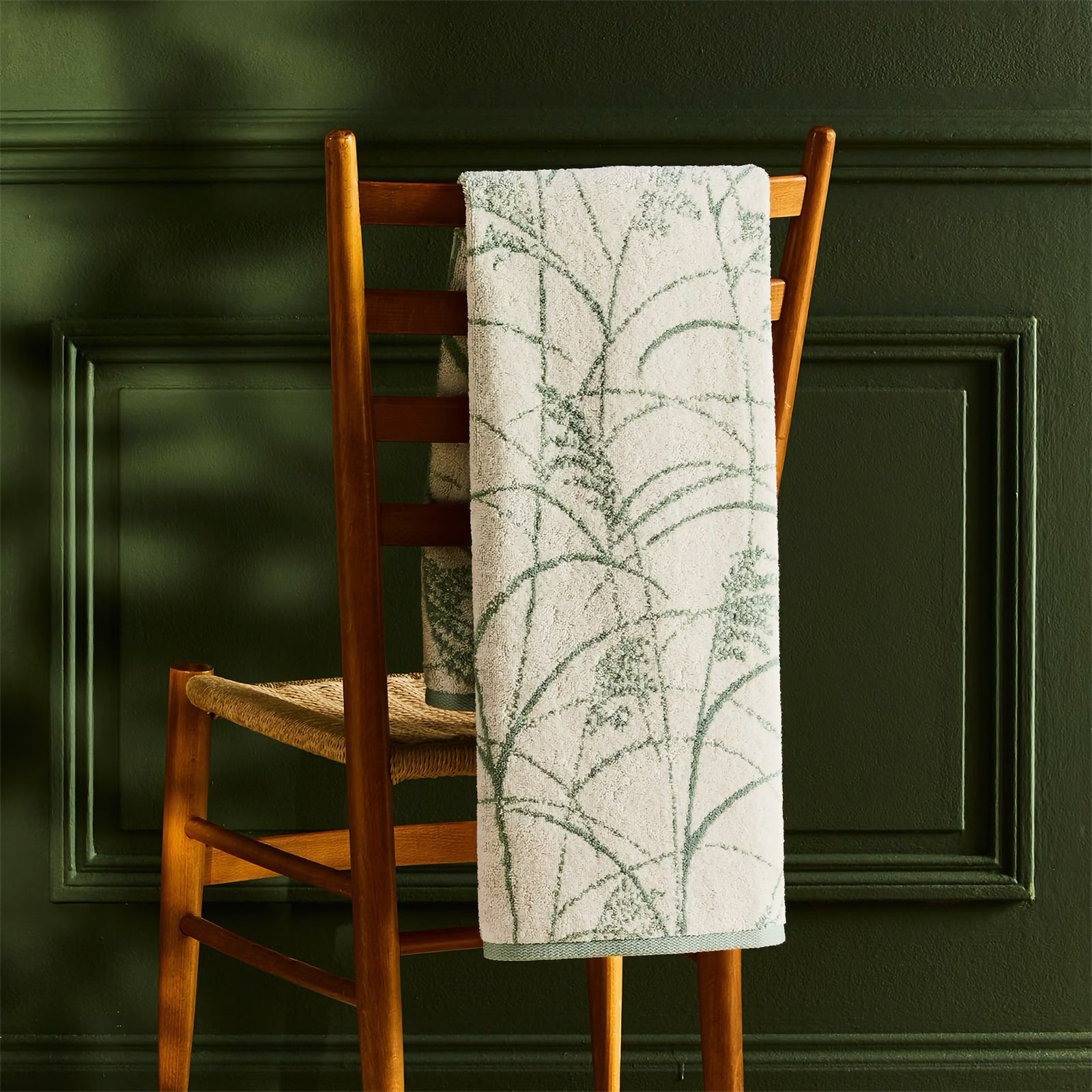 Yves Delorme Graminee Bath Towel hanging on chair