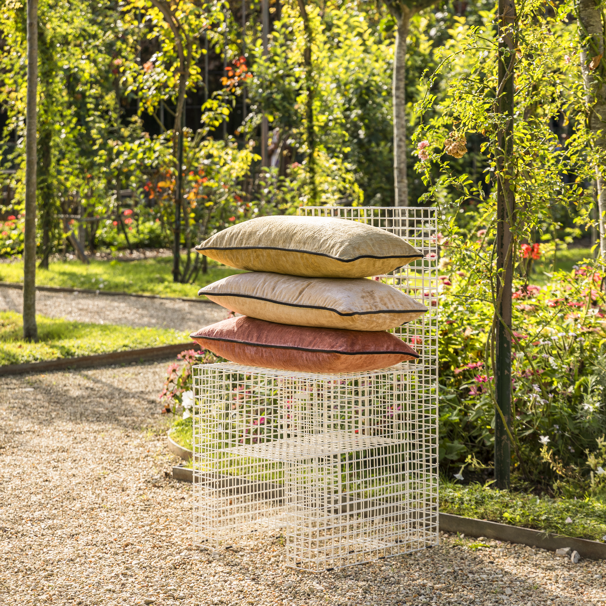 Stack of Yves Delorme Iosis Boromee Decorative Pillows in a Garden