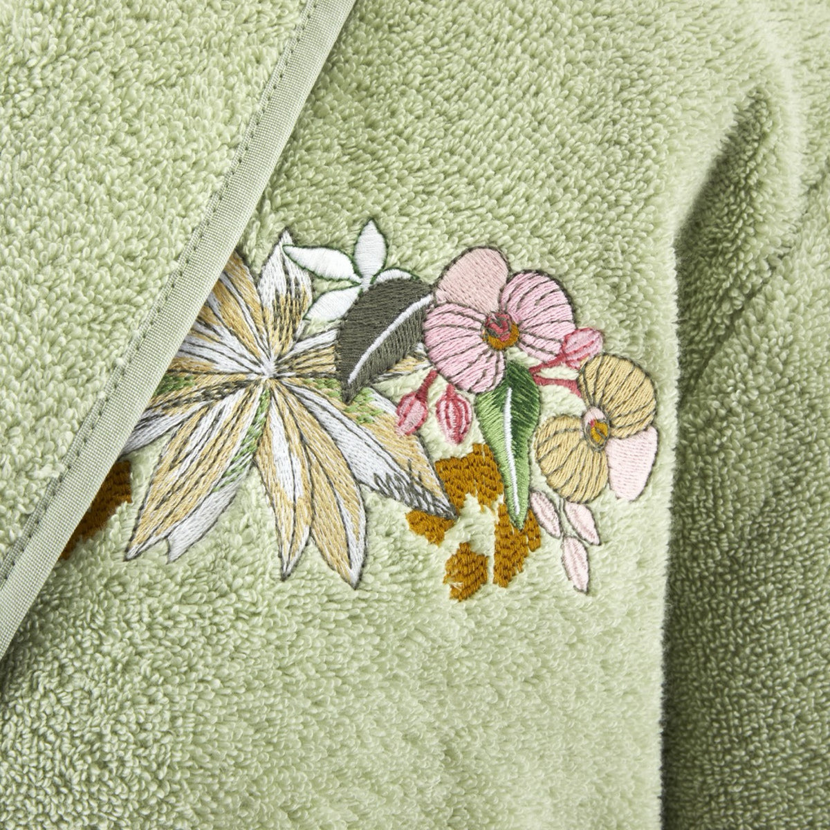Close-up of green textured fabric from the Orchidée Bath Collection, embroidered flowers in organically grown cotton