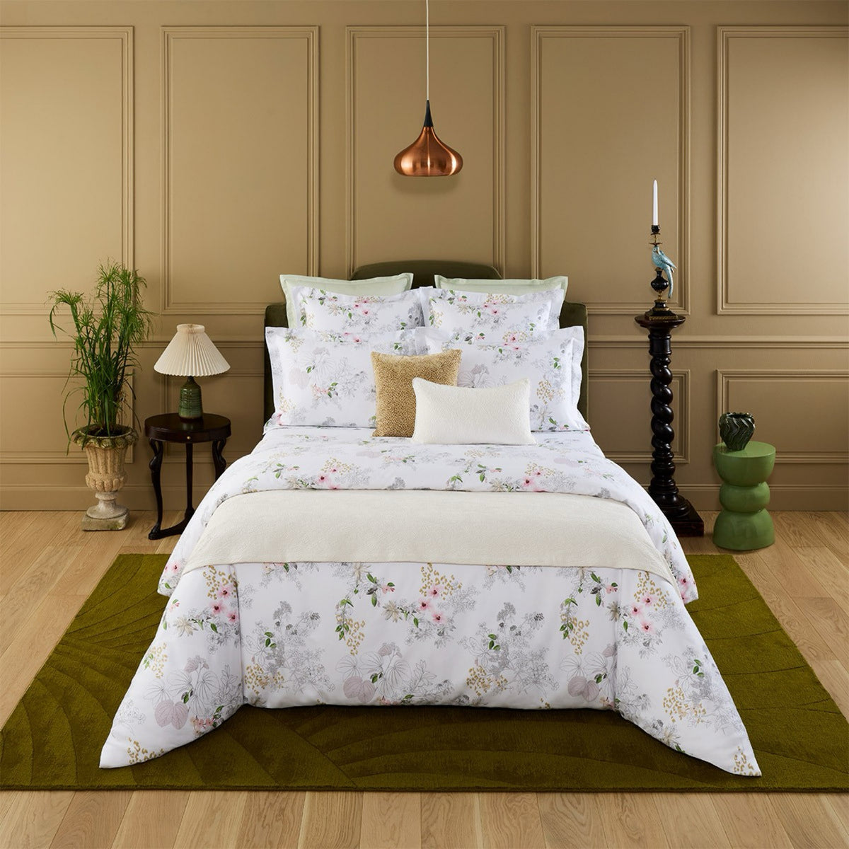 A neatly made bed with Yves Delorme Orchidée Bed Collection in a chic, tan-paneled bedroom