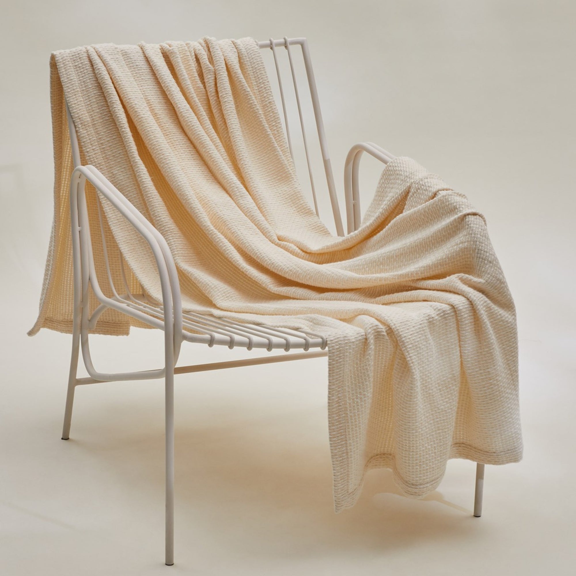 Lifestyle Image of Yves Delorme Transat Throw Hanging on a Chair in Celadon Color