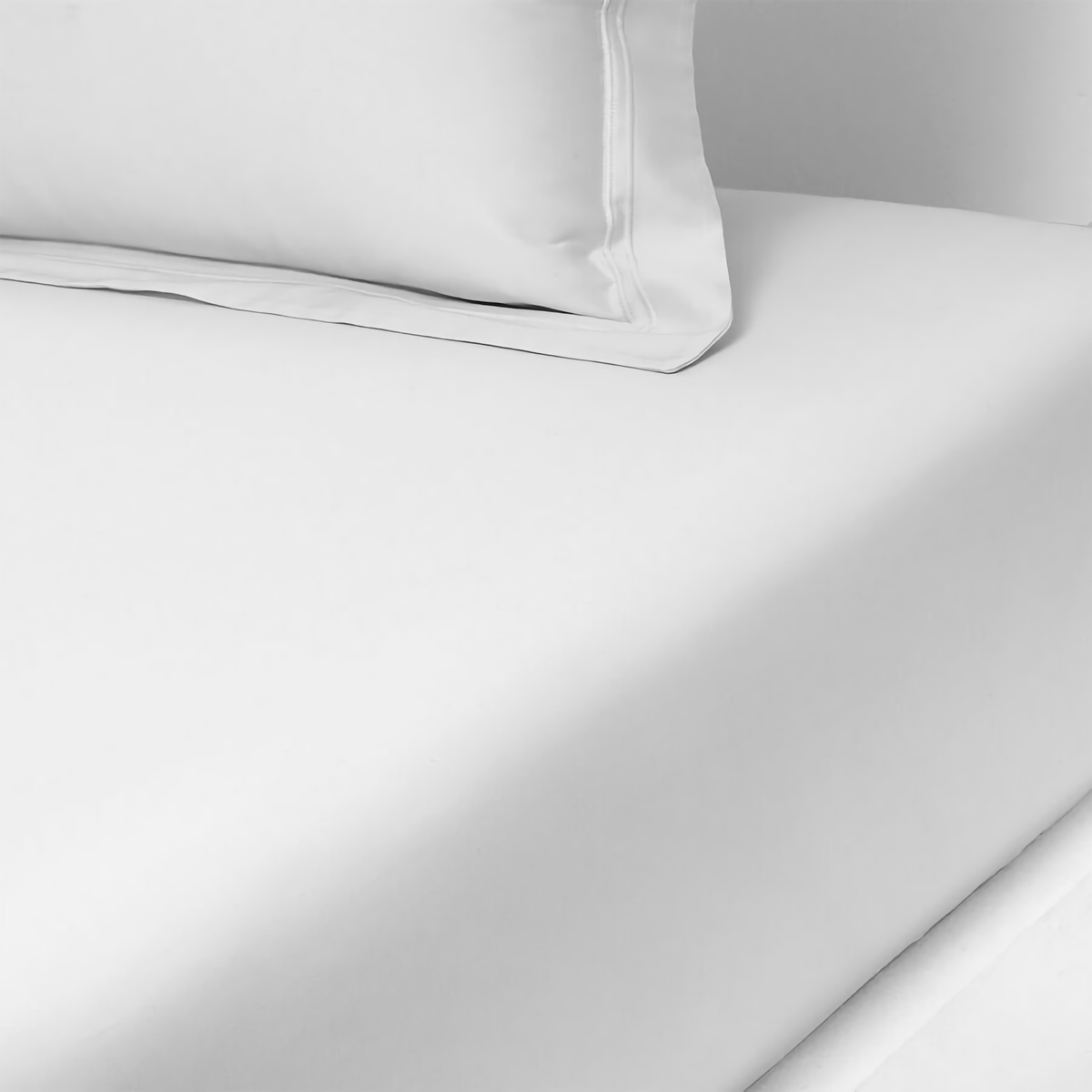 A neatly made bed with white sheets and a matching pillowcase against a plain white background.