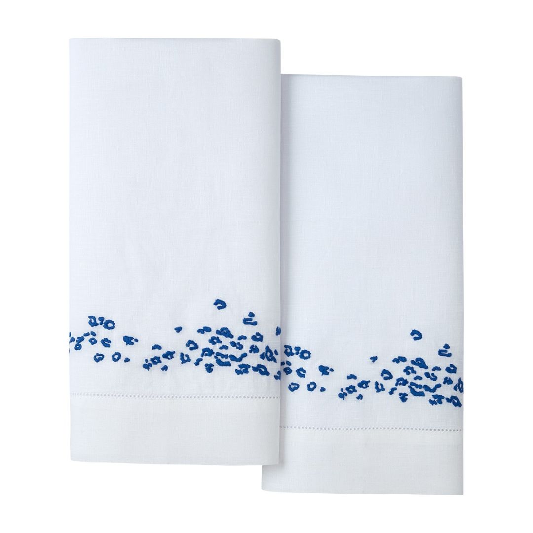 Two neatly folded white linen guest towel set with blue embroidery, displayed on a plain background.