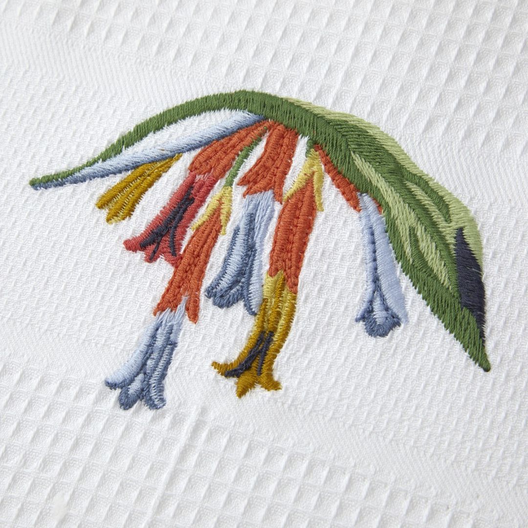 Embroidered design of colorful, tubular flowers and green leaves on Yves Delorme Eze Bath Collection bath linens.