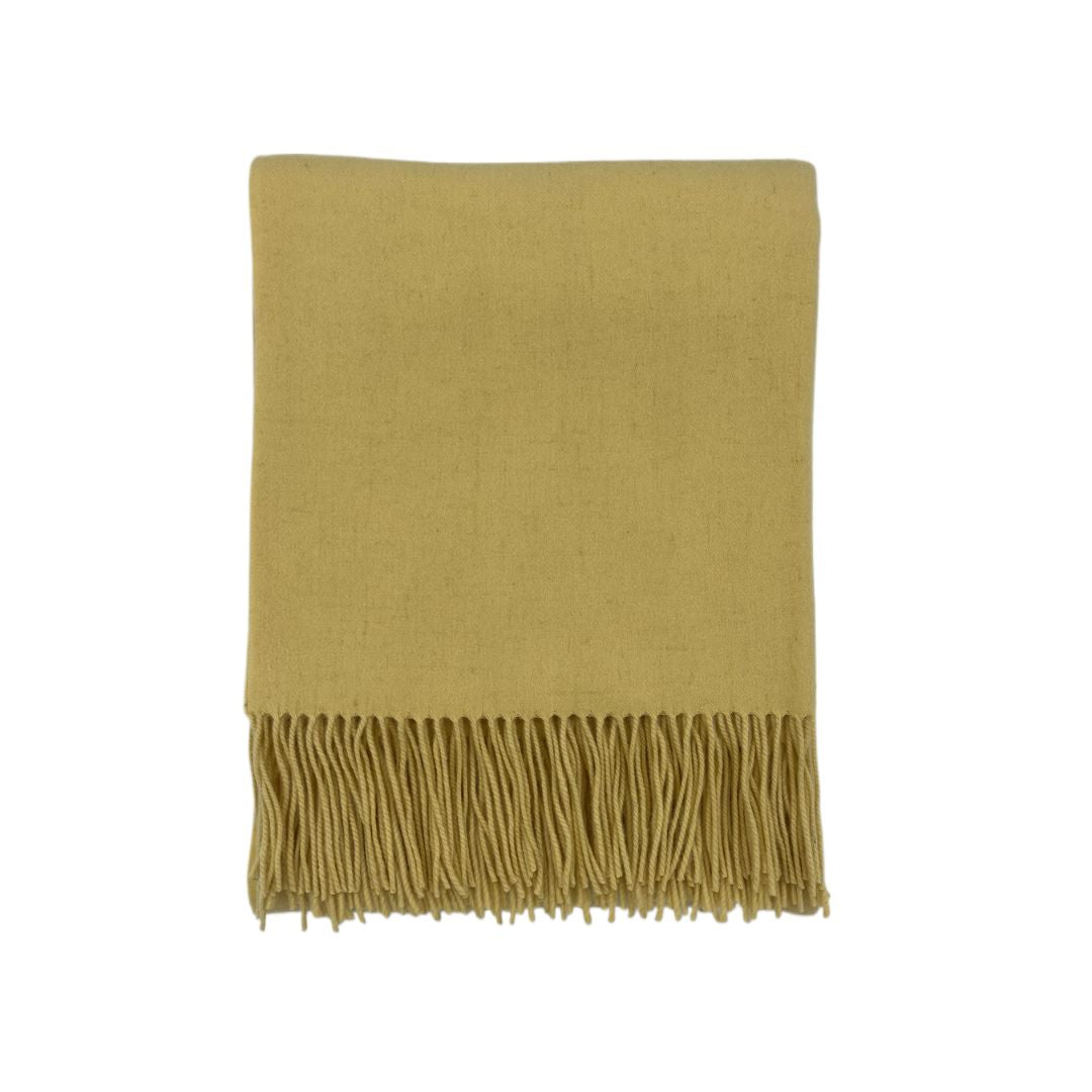 A folded mustard yellow scarf with fringe, inspired by merino cashmere throws, displayed on a white background.