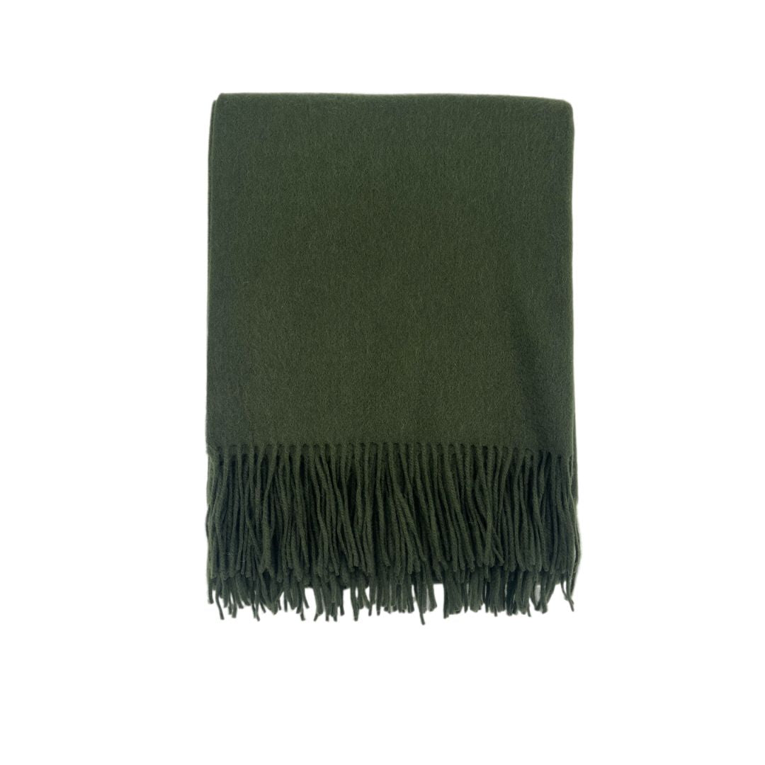 A folded solid colored blanket with fringe, displayed against a white background.