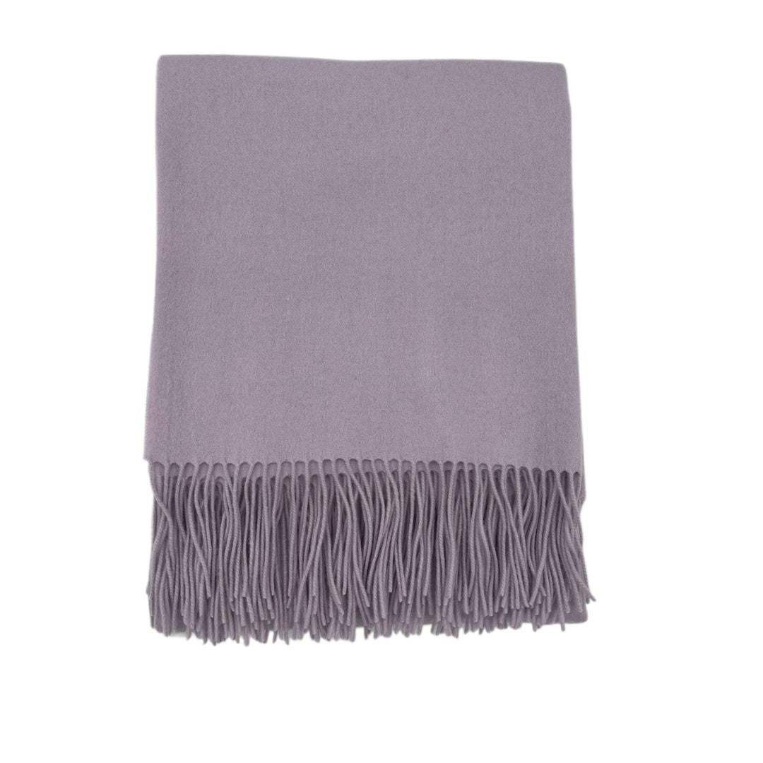 A folded lavender-colored merino cashmere throw with fringe on one end, displayed against a white background.