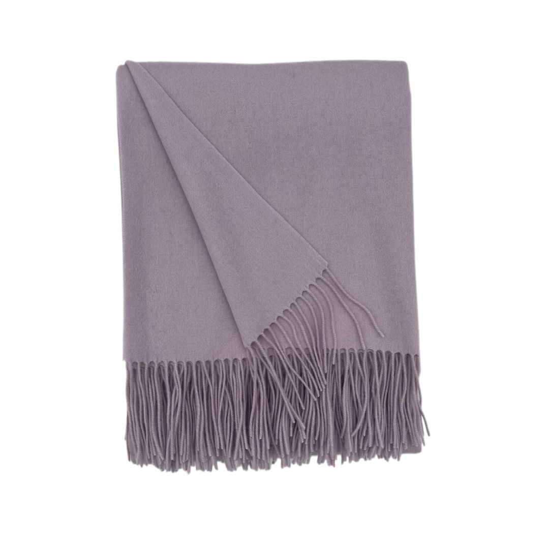 A folded merino cashmere throw with fringed edges, displayed on a white background.
