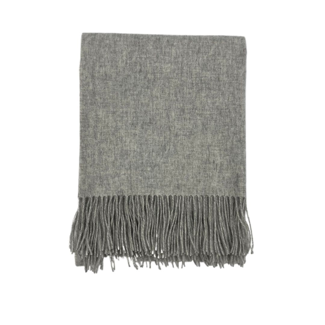 Folded grey wool scarf with fringe tassels, reminiscent of classic merino cashmere throws, on a white background.