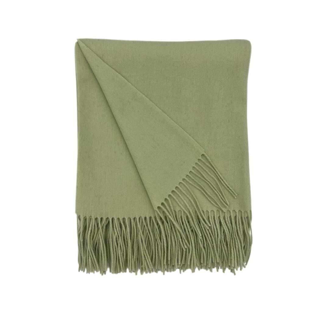 A solid colored blanket in light green is neatly folded on a white background.