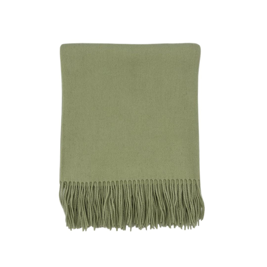 Folded solid colored blanket with fringed edges, crafted from woven blankets, displayed on a white background.