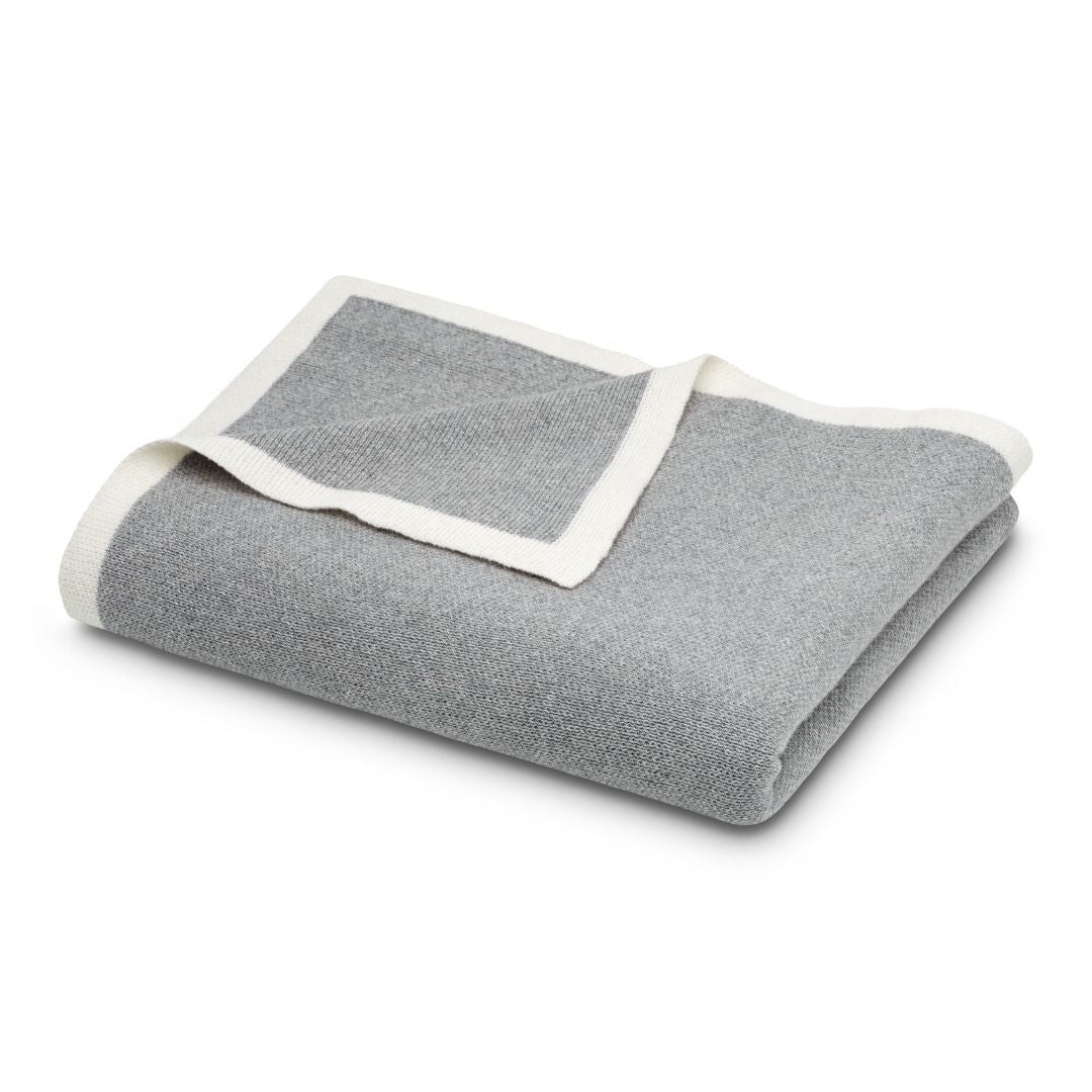Folded grey luxury knit throw blanket with a white border.