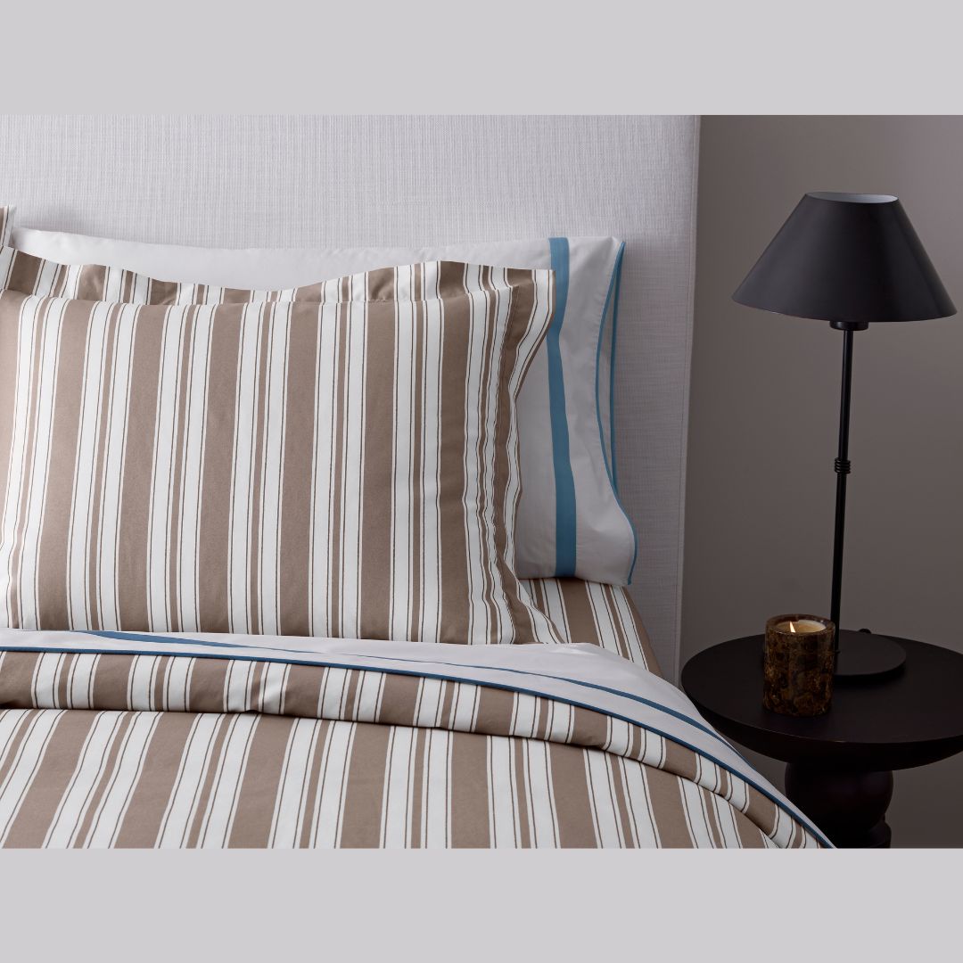 Striped bedding with a pillow and lamp in a bedroom setting
