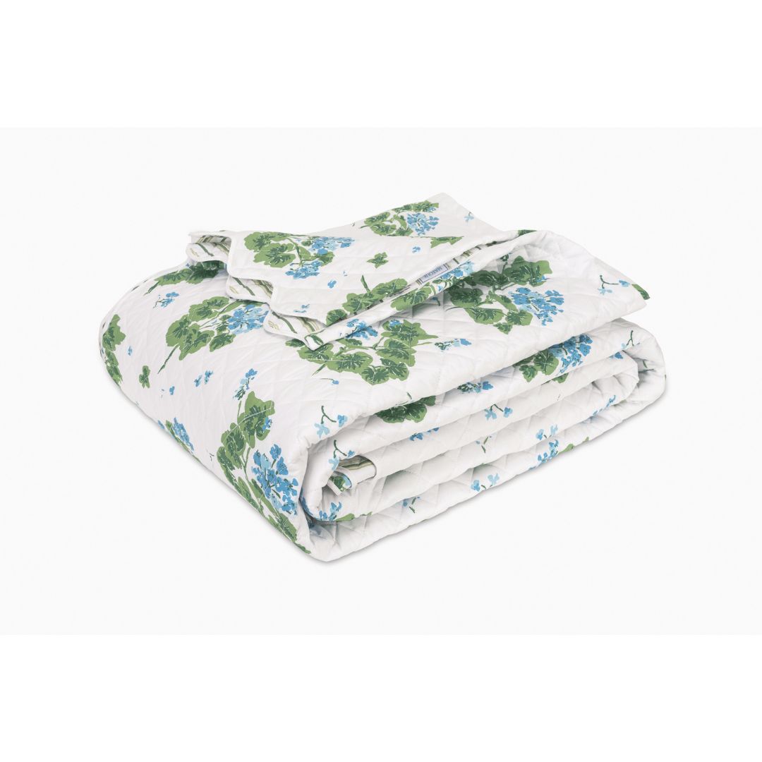 Folded floral quilt with green and blue pattern on a white background