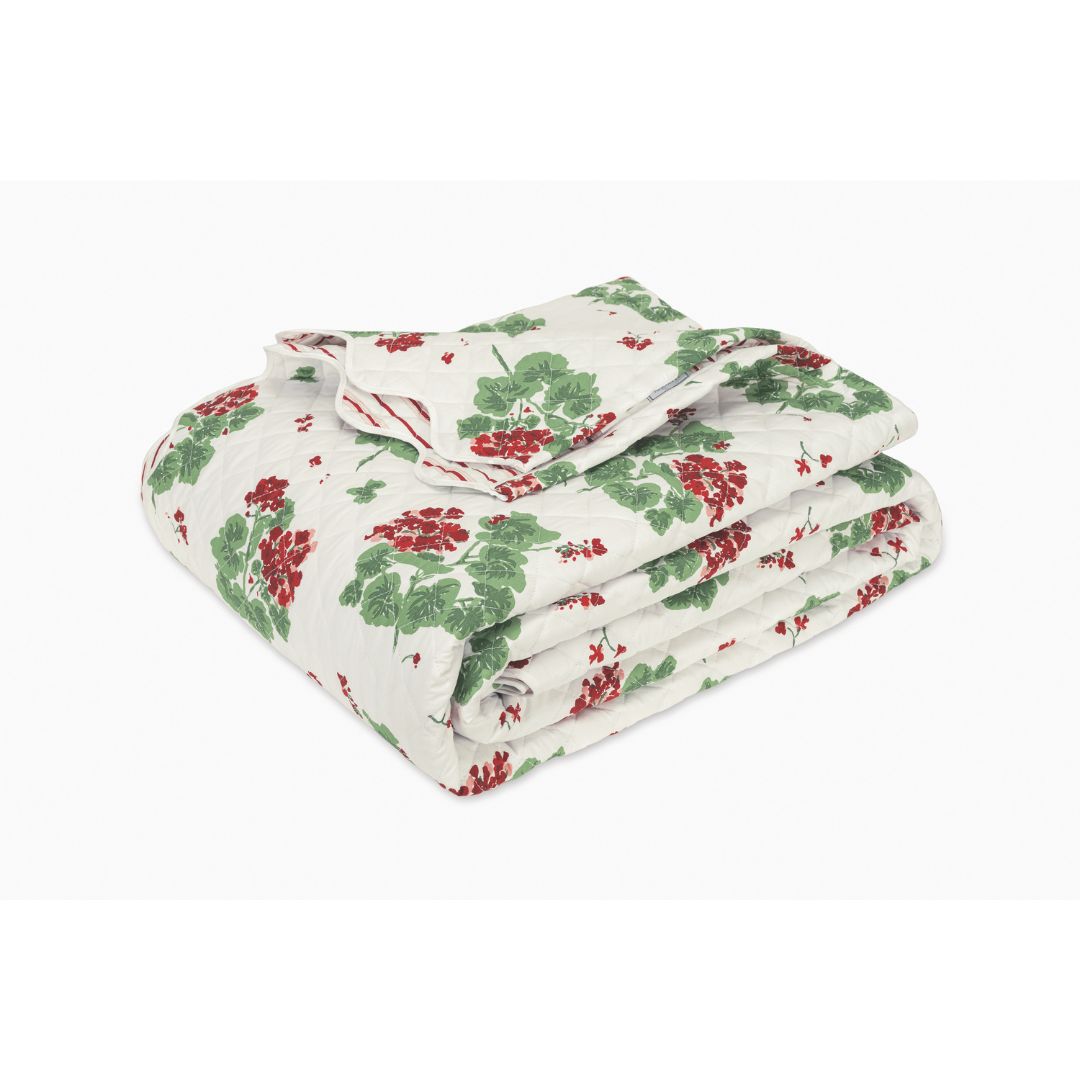 Folded floral blanket with red and green pattern on a white background