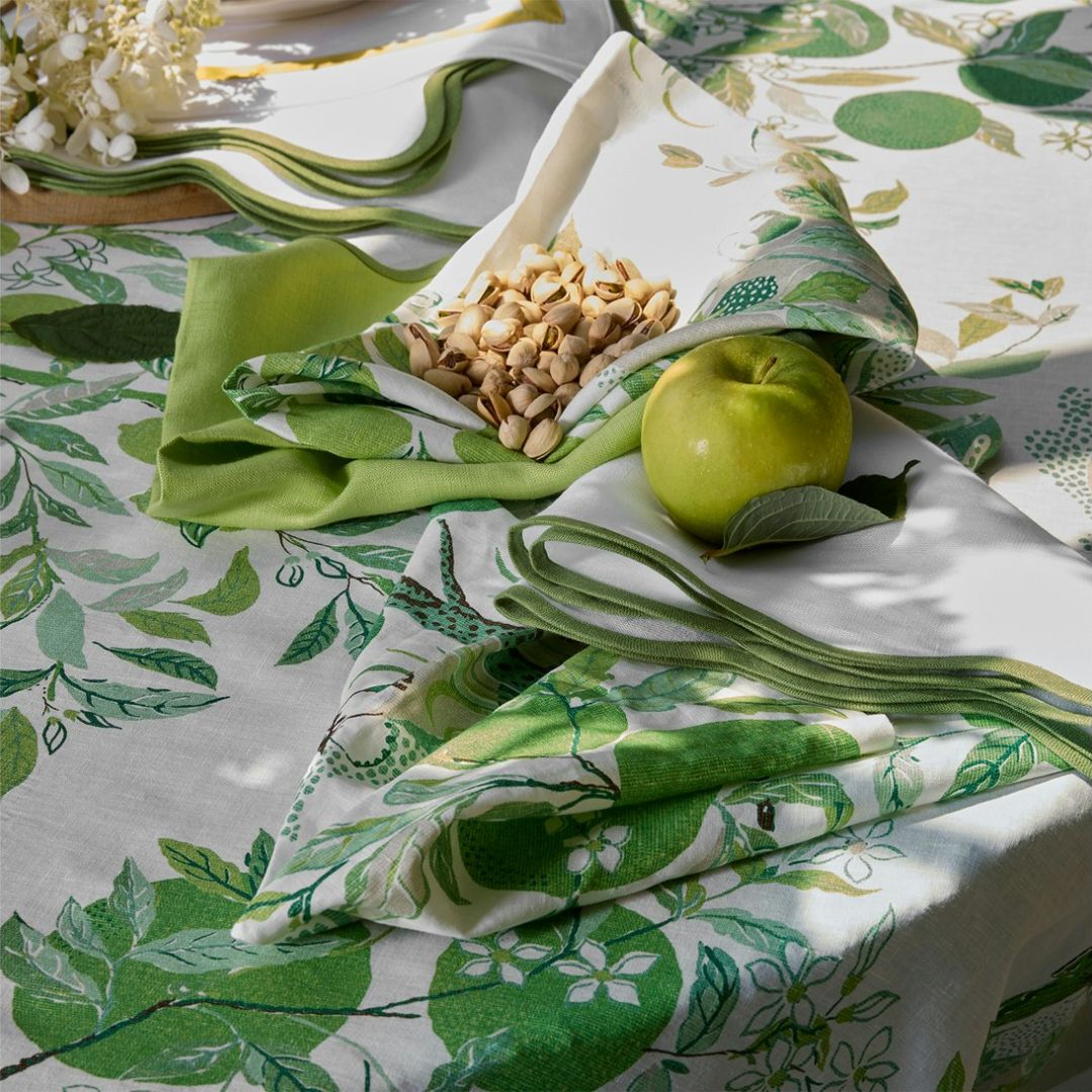 Table setting with green and white patterned tablecloth, napkins, and a green apple. shown with citrus garden in grass and lowell in canary
