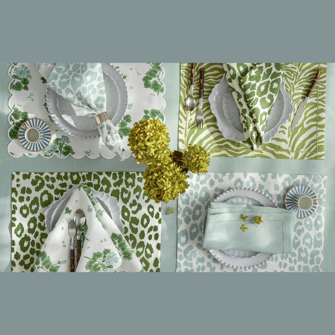Four place settings with Matouk table linens, scalloped plates, napkins, and yellow flowers in the center.