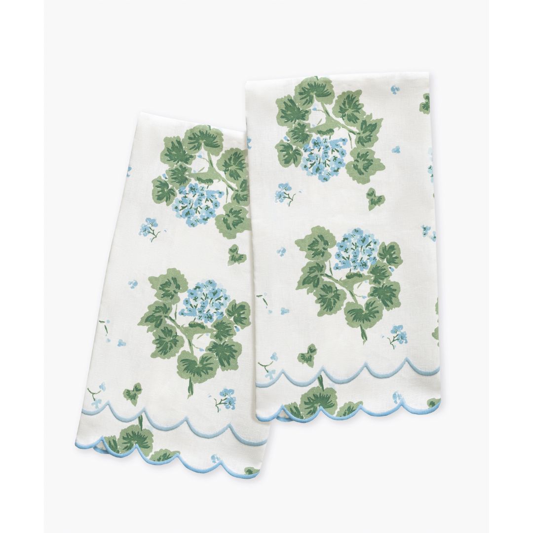 Two white towels with green and blue floral patterns on a white background