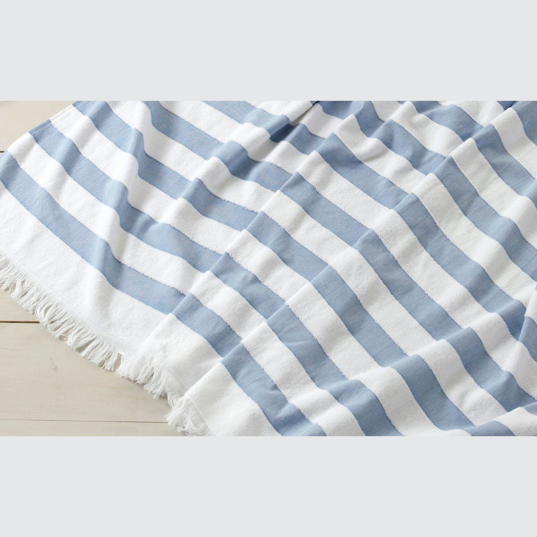 Striped blue and white beach towel on a light wooden surface
