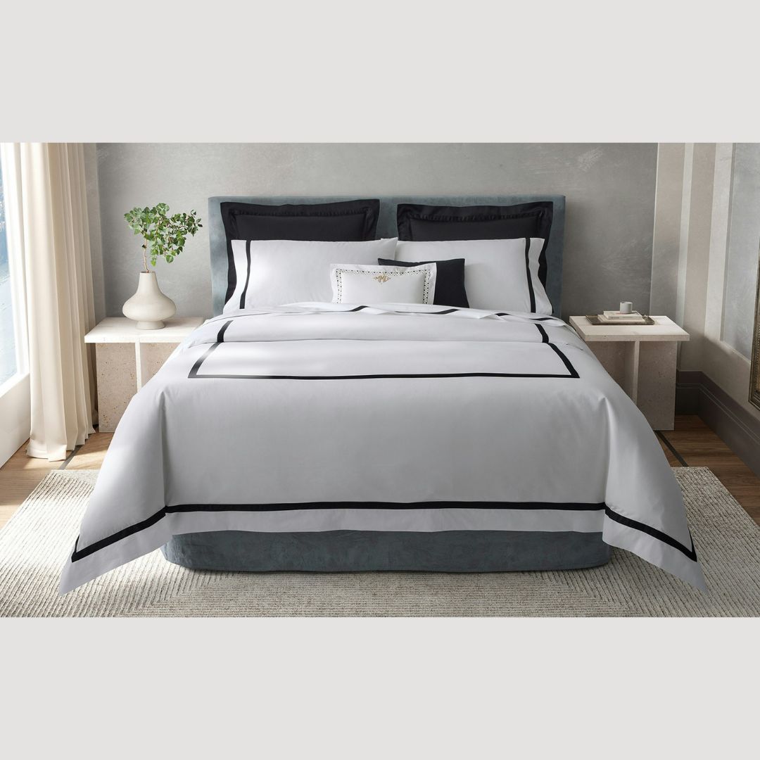 A neatly made bed with 600 thread count duvet covers, flanked by nightstands, in a bright, modern bedroom.